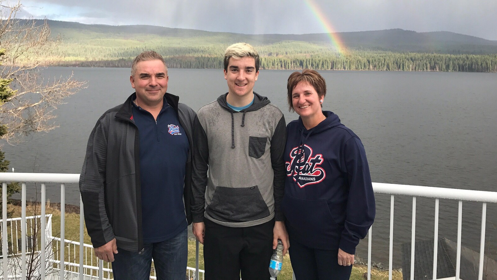 Adam Herold pose avec ses parents, Russell et Raelene Herold, devant un lac.