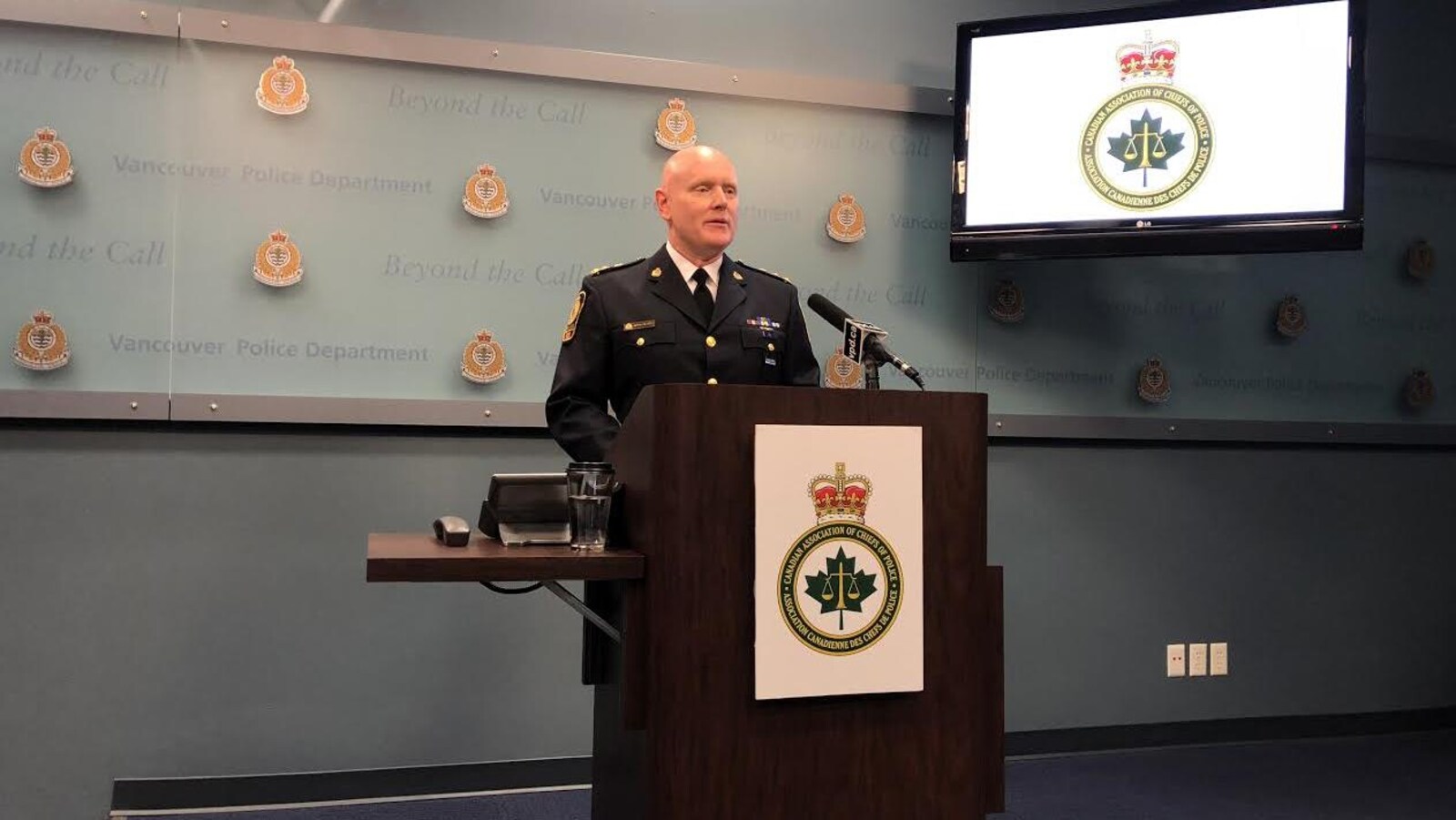 Adam Palmer en uniforme de policier derrière un lutrin au poste de police de Vancouver.