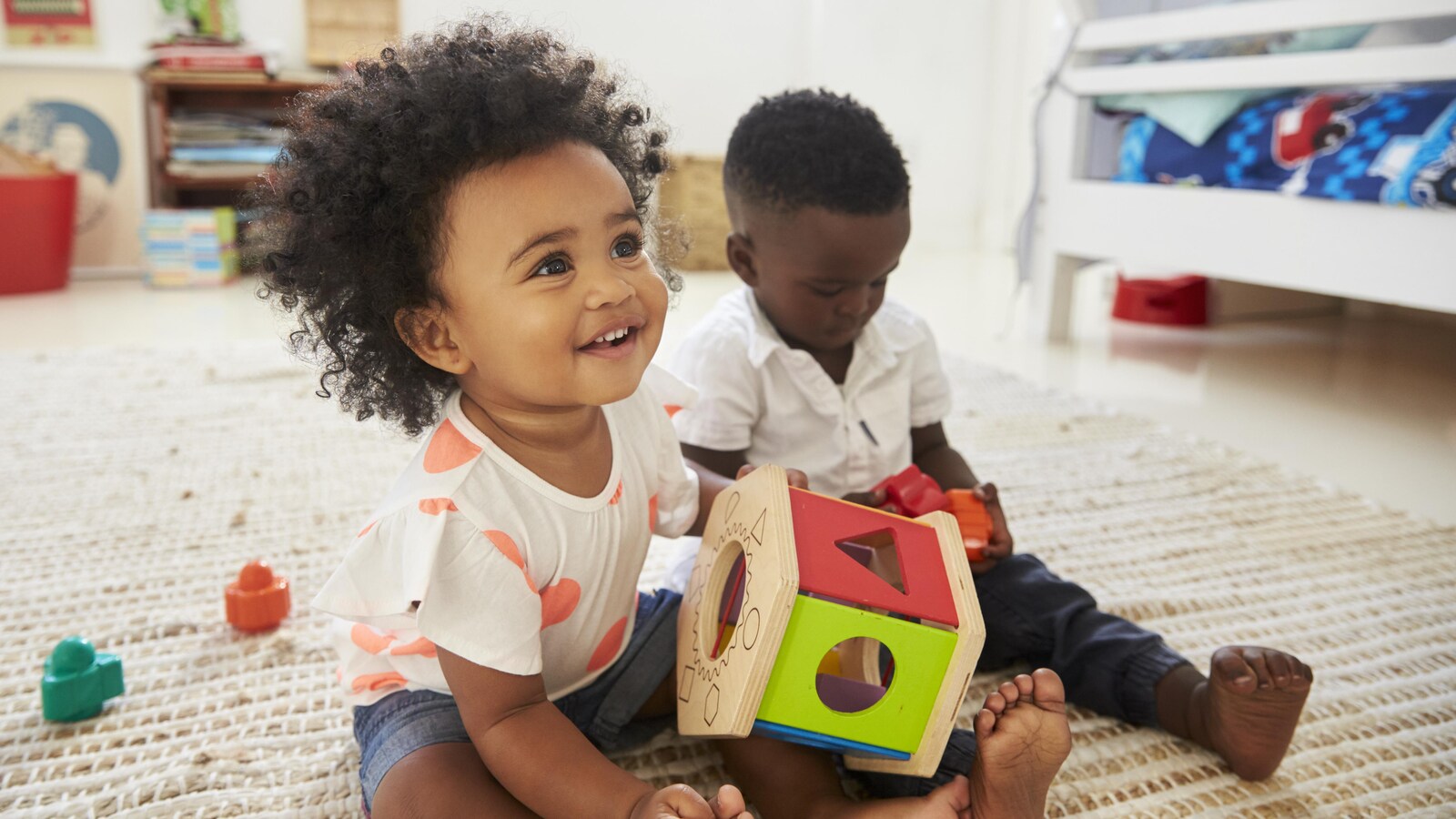 Deux jeunes enfants assis sur un tapis.