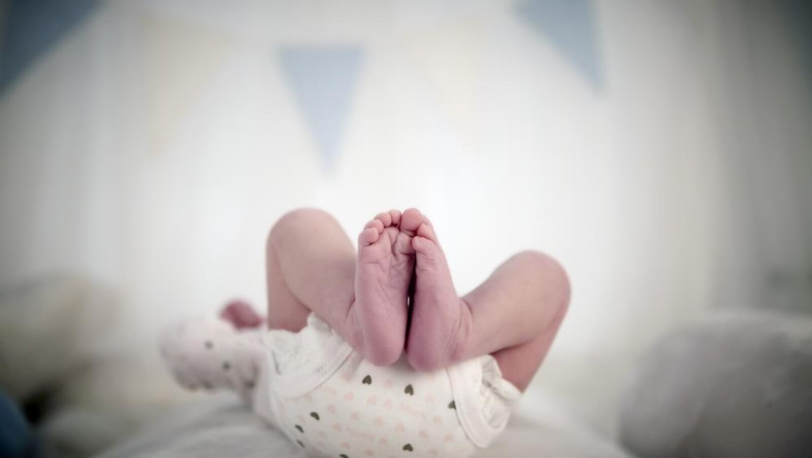 On voit les jambes d'un bébé couché sur le dos.