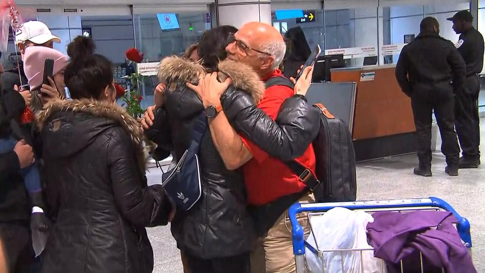 Des gens se serrent dans leurs bras à l'aéroport.