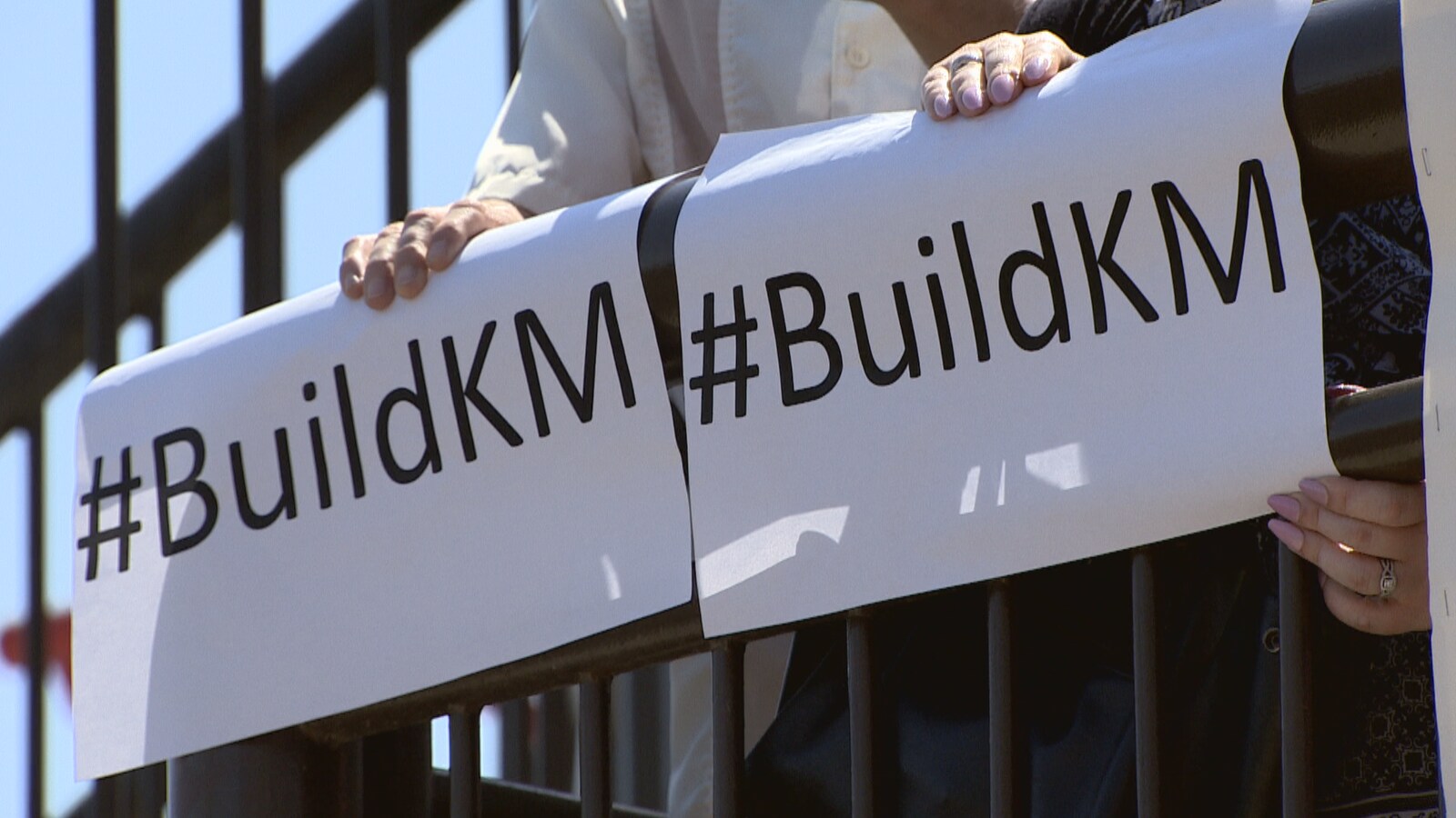Deux affiches sur lesquelles il est inscrit # Build KM, tenues par des manifestants, à Calgary.