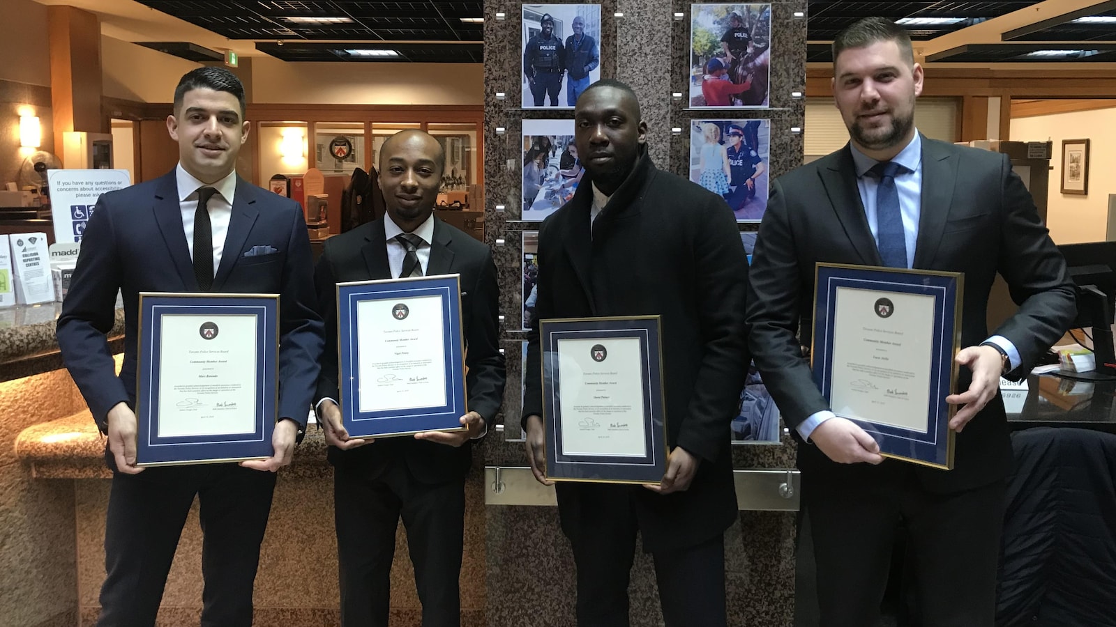 Quatre hommes posent avec leur prix honorifique dans les mains.