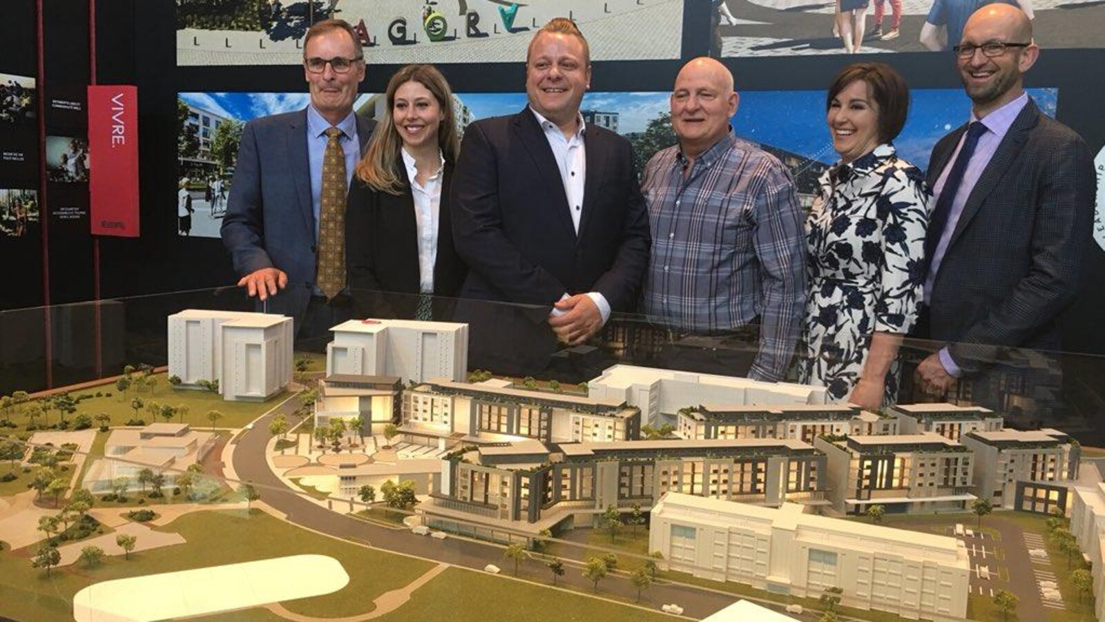 Un groupe devant une maquette d'un grand projet immobilier.