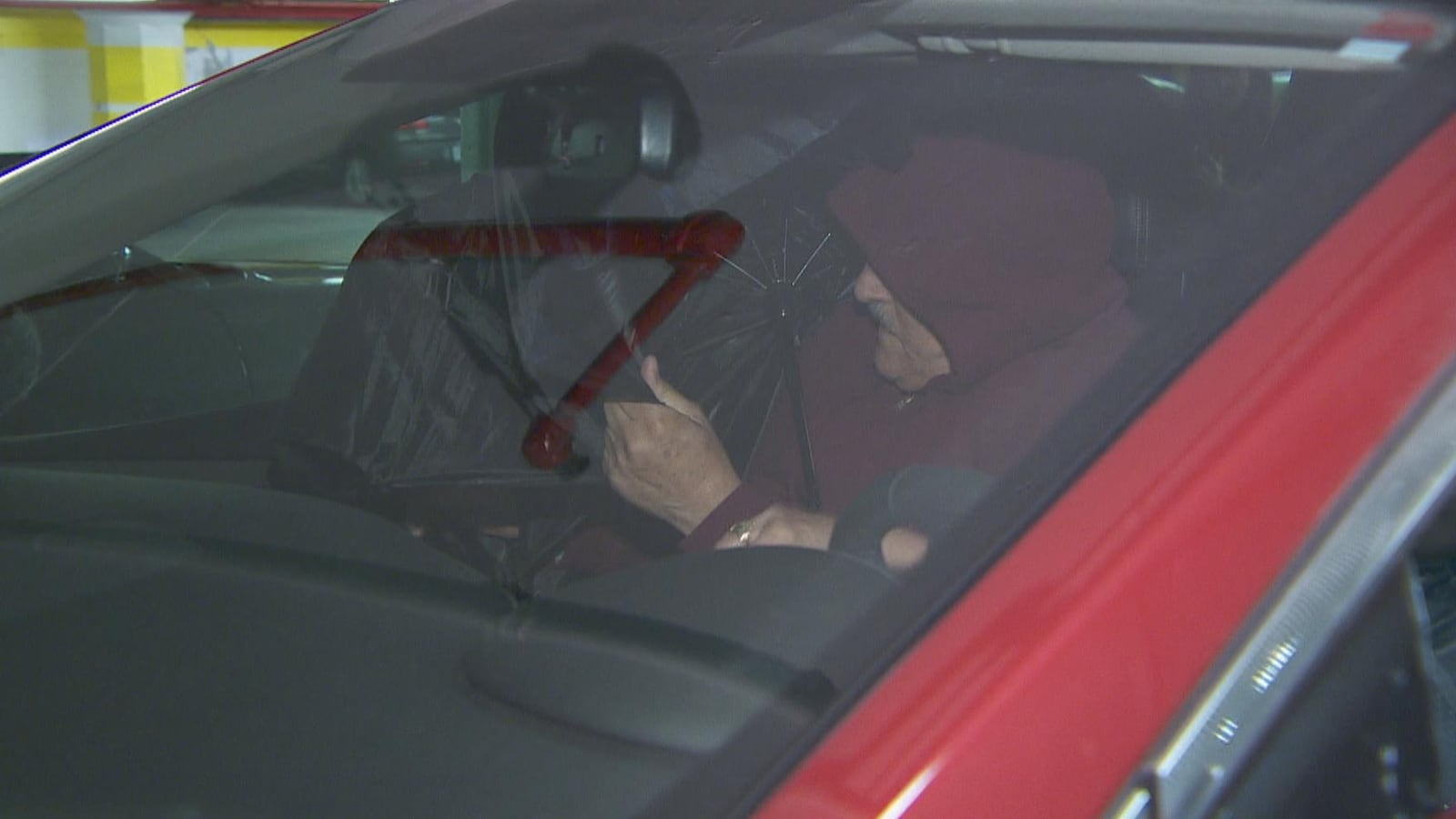 On voit Claude Trachy qui entre dans sa voiture pour échapper à la vigilance des médias en sortant du tribunal.