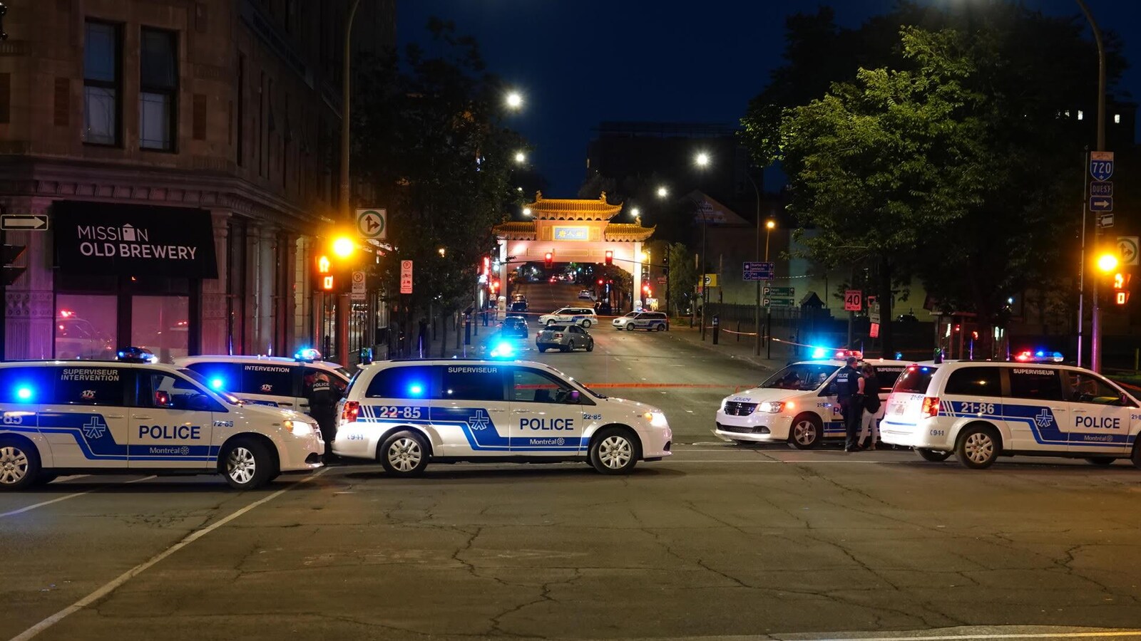 Des voitures de police barrent une rue dans la nuit. La pagode illuminée nous montre que nous sommes sur le boulevard Saint-Laurent