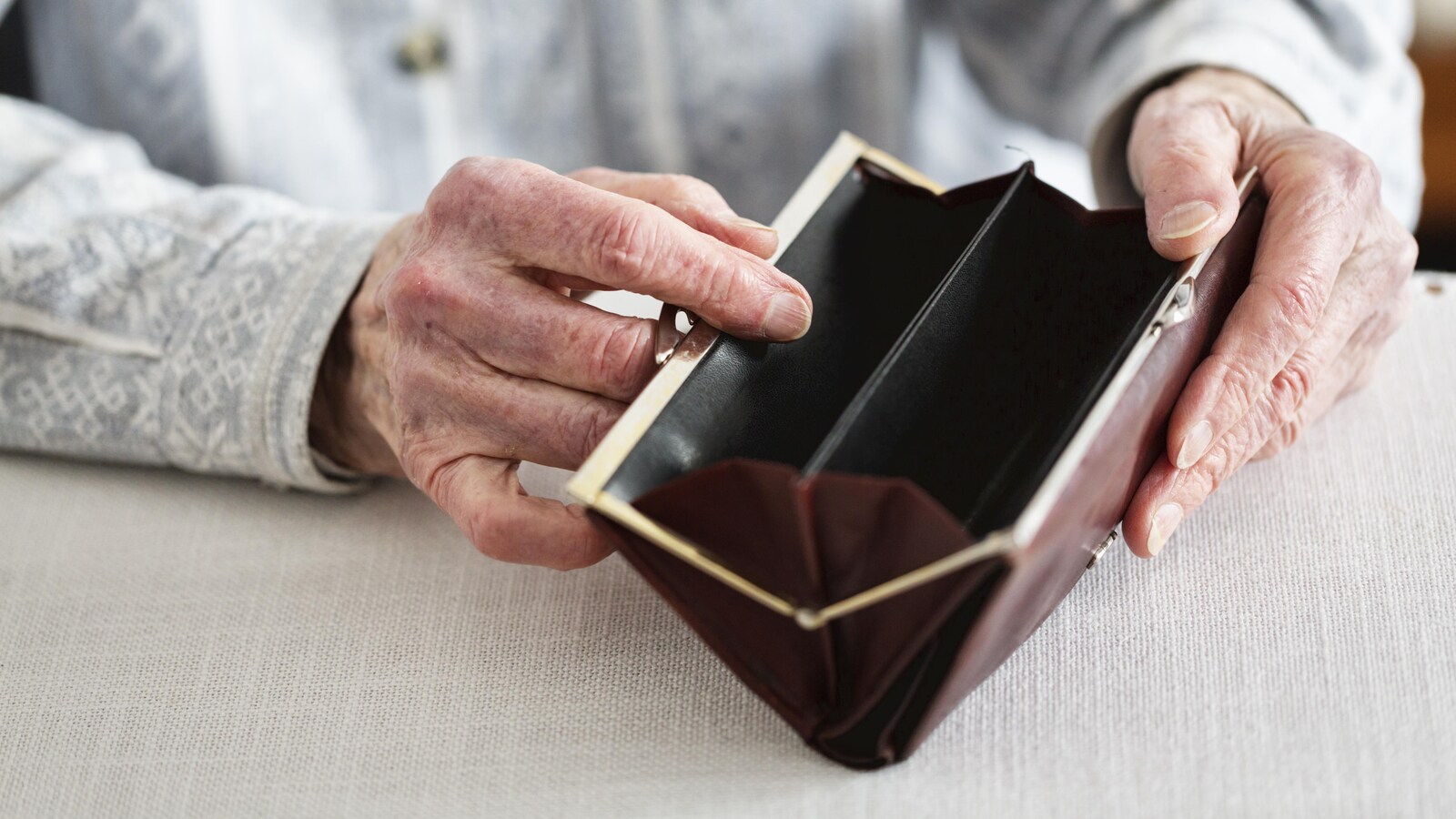 Une personne âgée tient une porte-feuille vide.