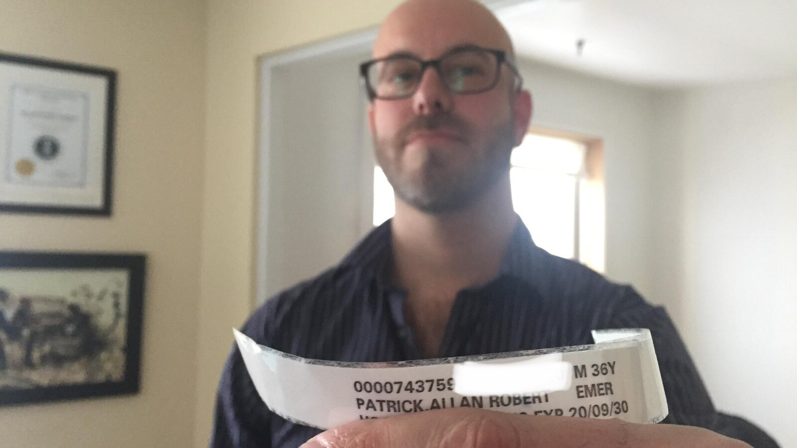Un homme montre à la caméra un bracelet d'hôpital portant son nom.