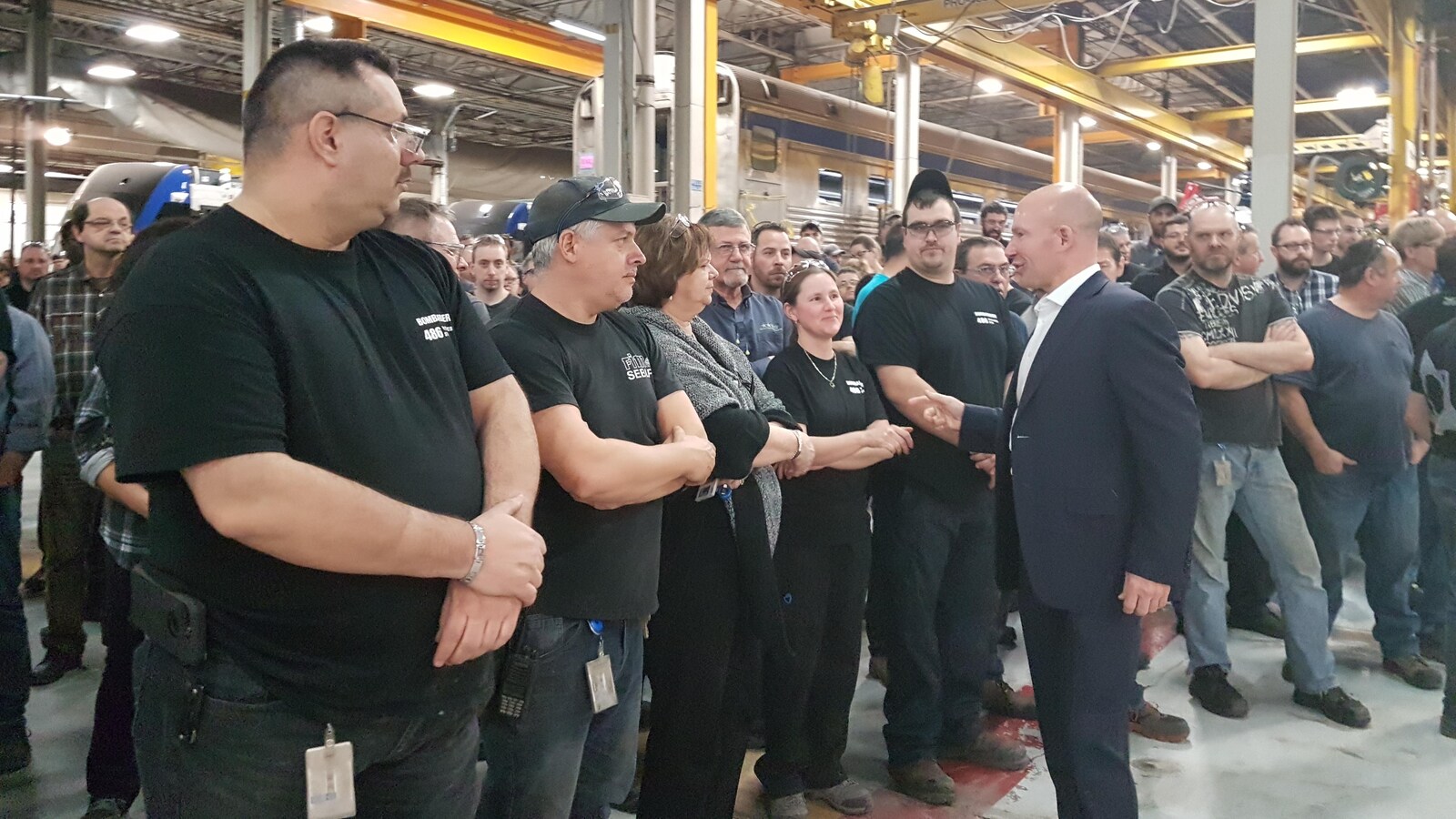 Alain Bellemare discute avec une poignée d'employés, en ligne pour lui serrer la main.
