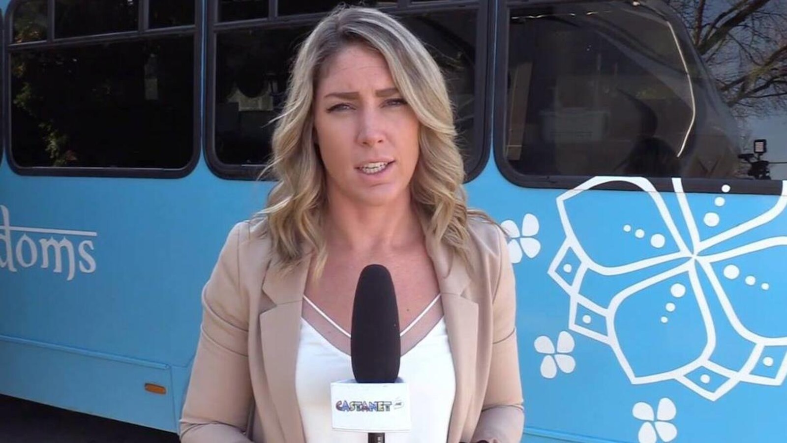Une femme regarde la caméra avec un micro dans les mains.