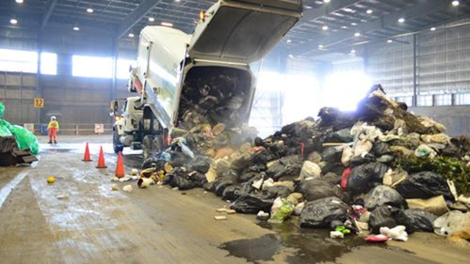 Un camion-benne déverse des sacs de déchets dans un hangar.