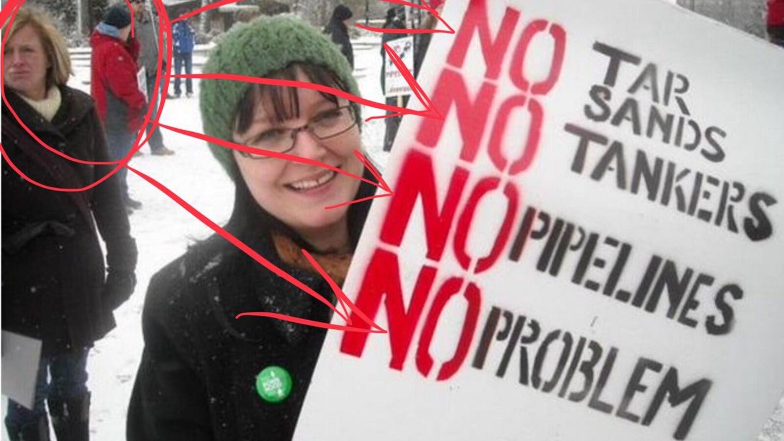 Rachel Notley apparaît en arrière-plan de la photo d'une manifestante portant une pancarte opposée aux pipelines, aux sables bitumineux et aux pétroliers.
