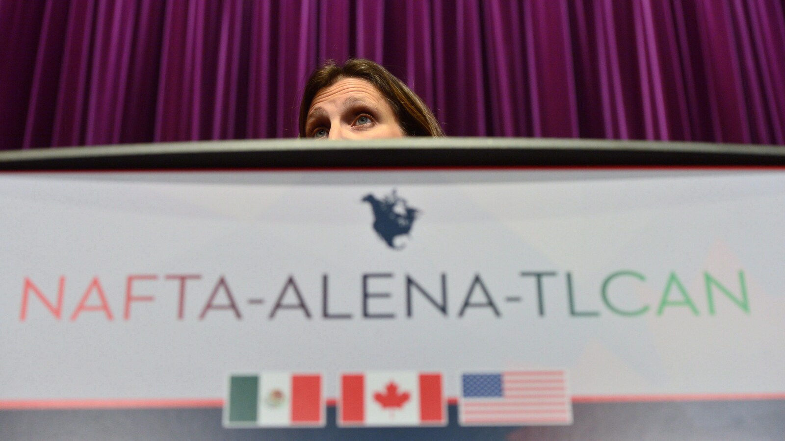 La tête de la ministre des Affaires étrangères, Chrystia Freeland, derrière un lutrin où on peut lire NAFTA-ALENA-TLCAN.