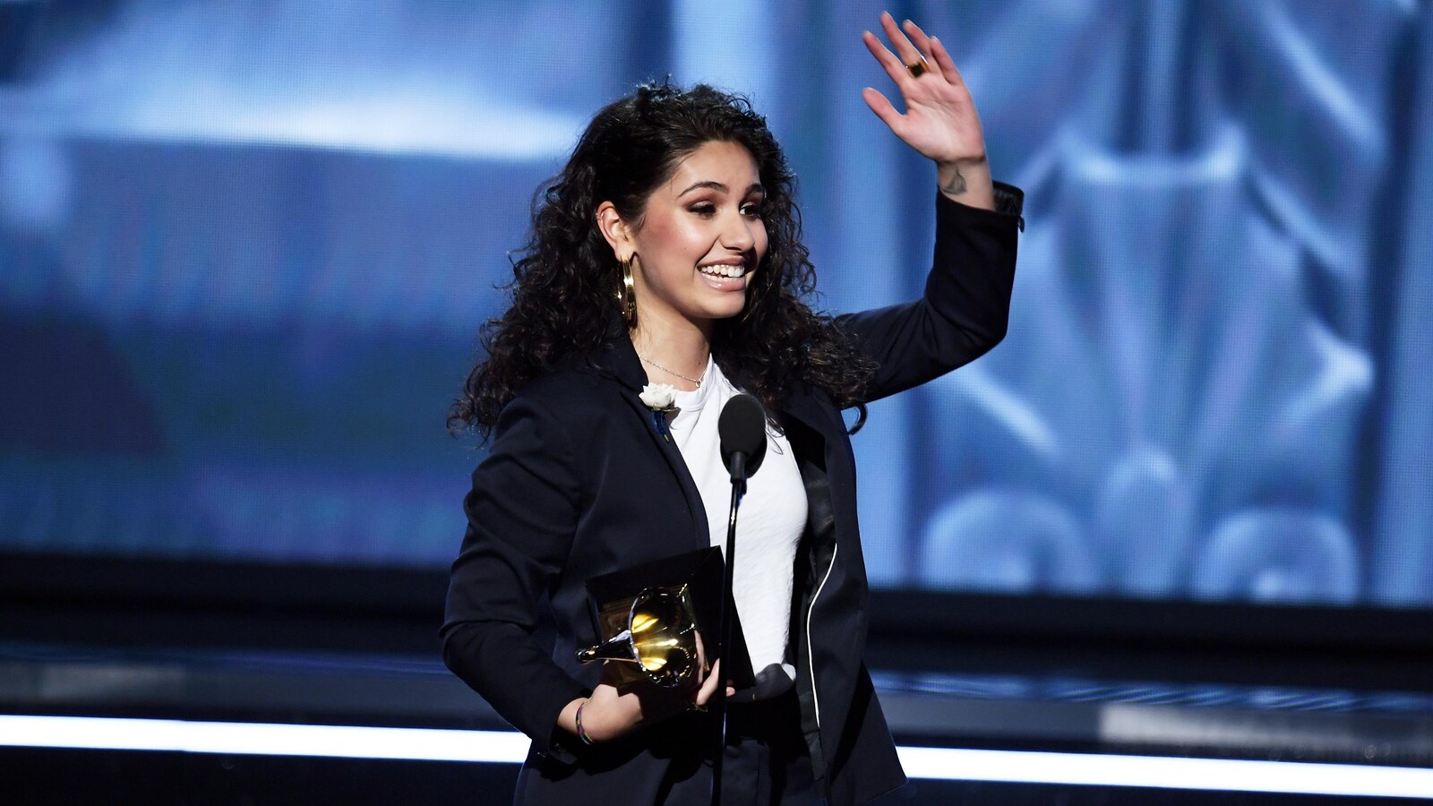 Alessia Cara salue sur scène, son trophée à la main.