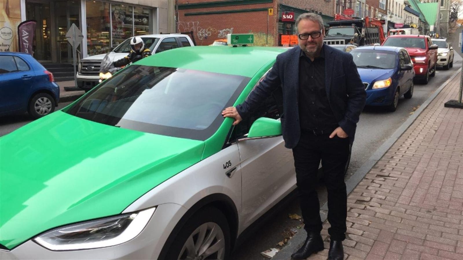 Le propriétaire de Téo Taxi, Alexandre Taillfer, prend la pose devant une voiture de la flotte.