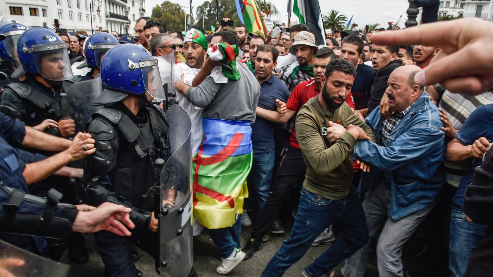 Manifestants et policiers se font face, plusieurs personnes en retenant d'autres.