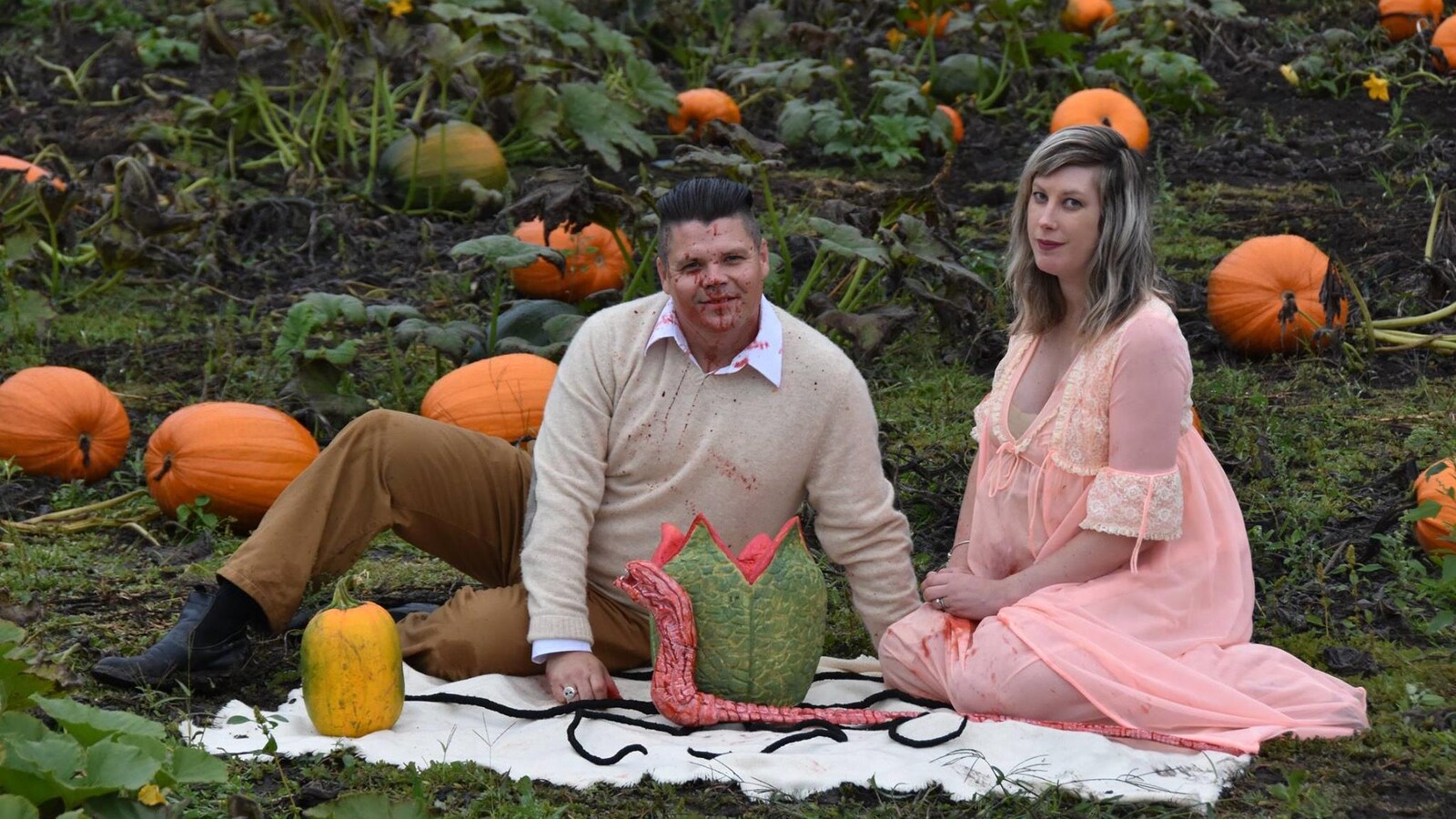 Todd et Nicole Cameron sont assis au milieu d'un champ de citrouilles avec une sorte d'extraterrestre en forme de gros ver.