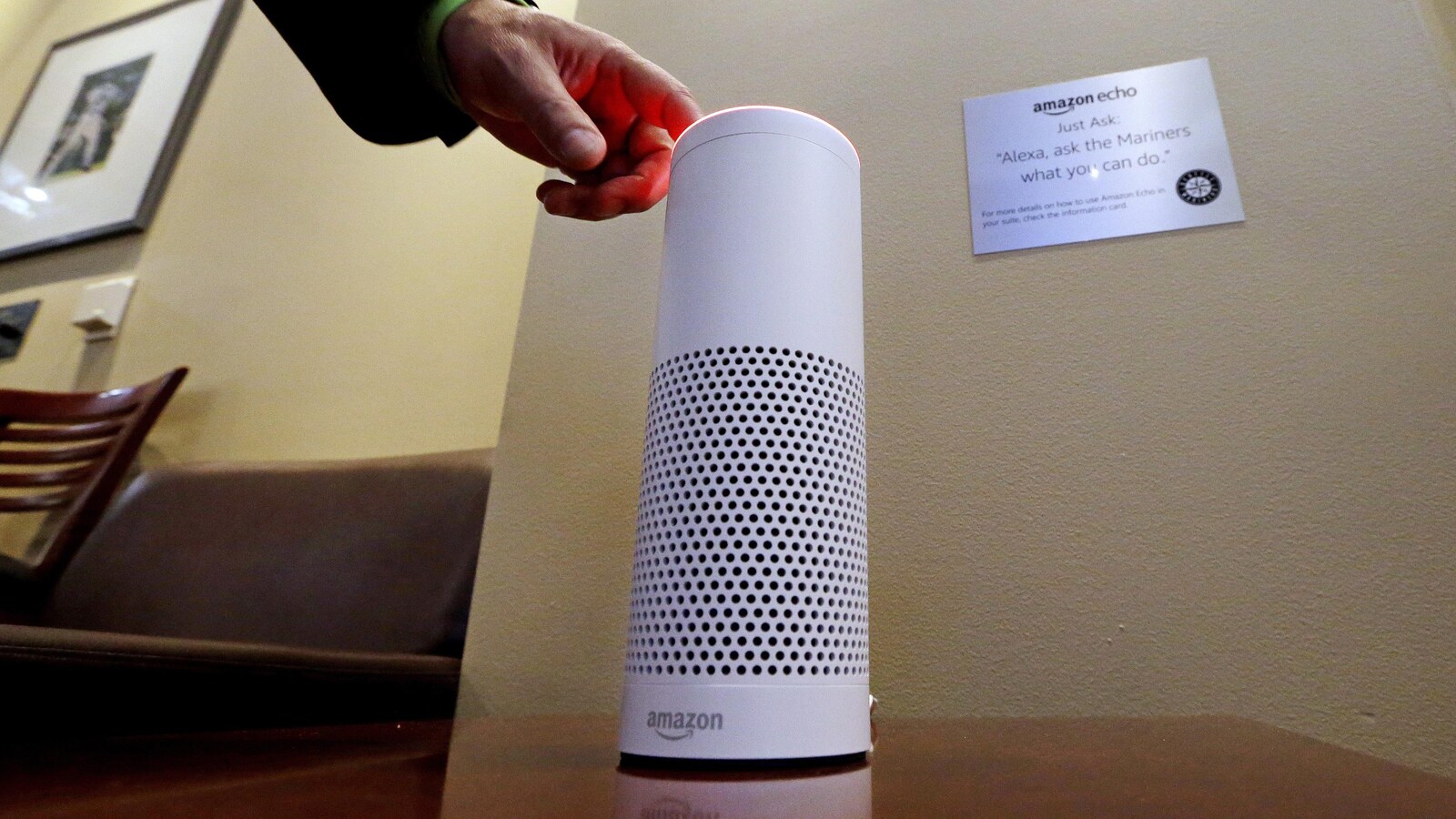 Une main allume l'assistant personnel intelligent Echo, un appareil fabriqué par Amazon