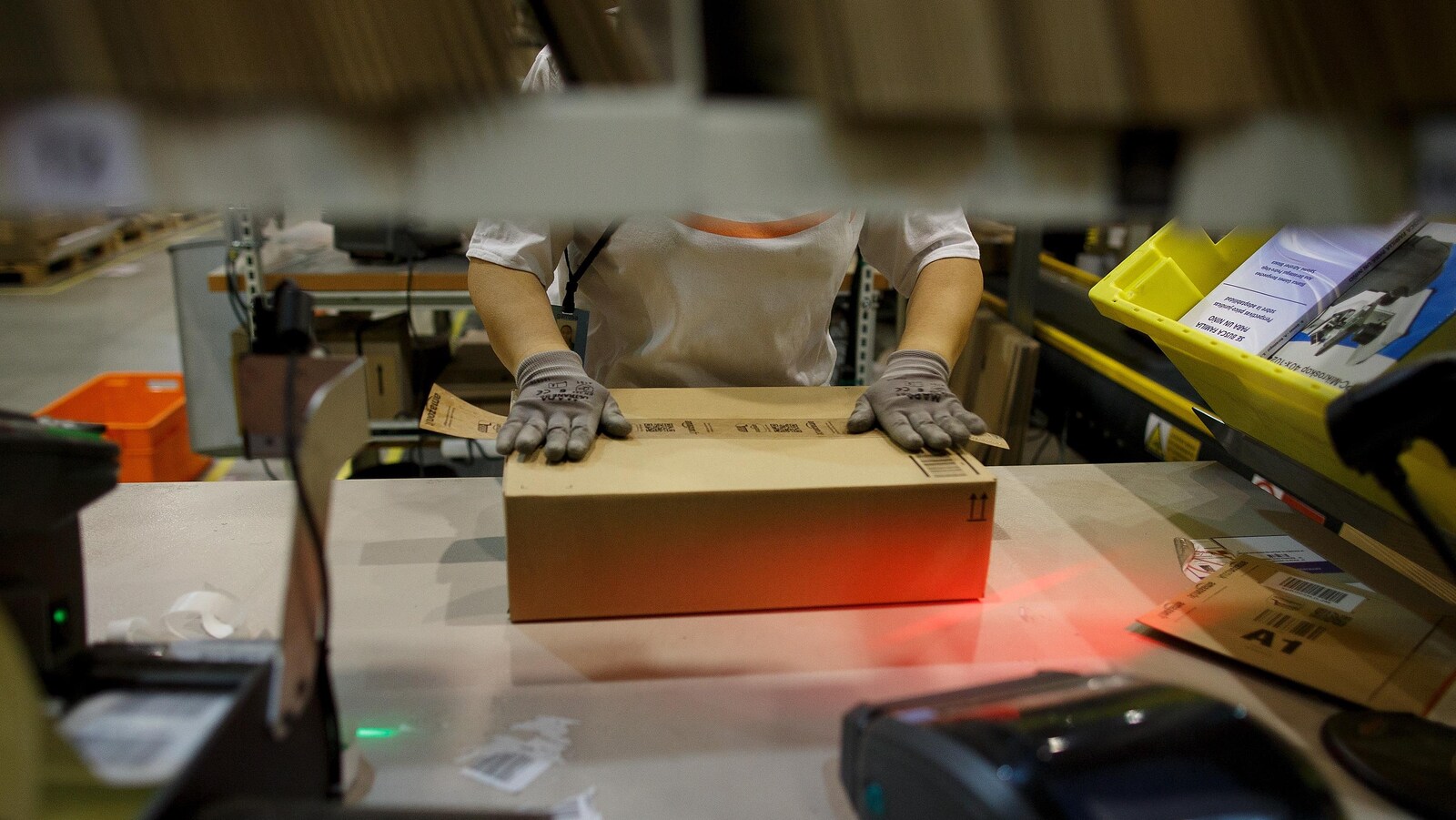Une personne manipule une boîte de carton sur une table de travail.
