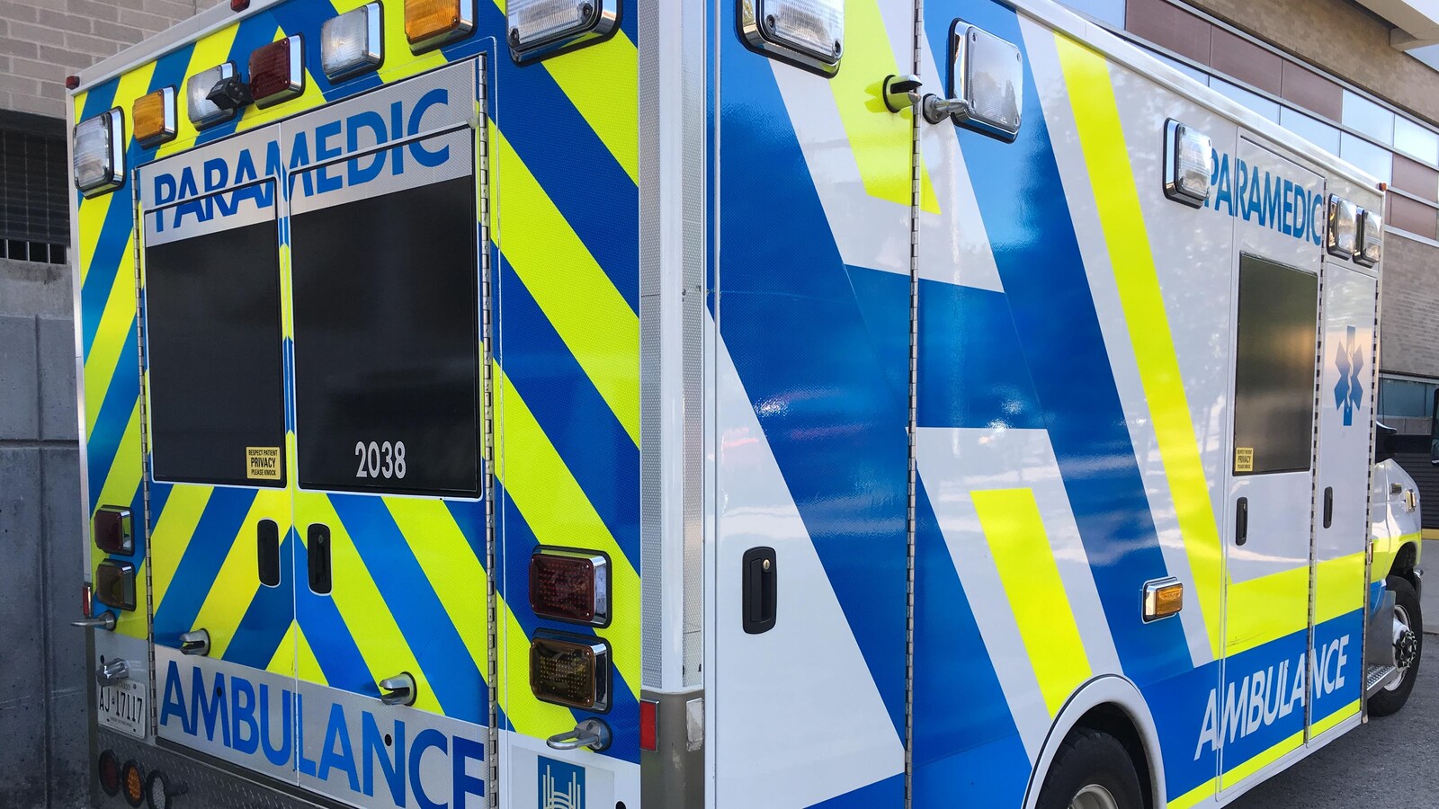 Photo d'une ambulance aux couleurs bleu, jaune et blanc à l'arrêt.