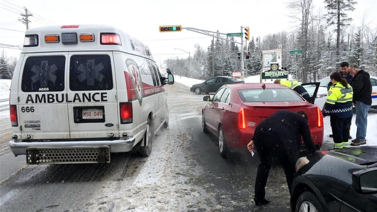 Une ambulance, en hiver, est arrêtée près d'une voiture. Les paramédicaux parlent au conducteur.