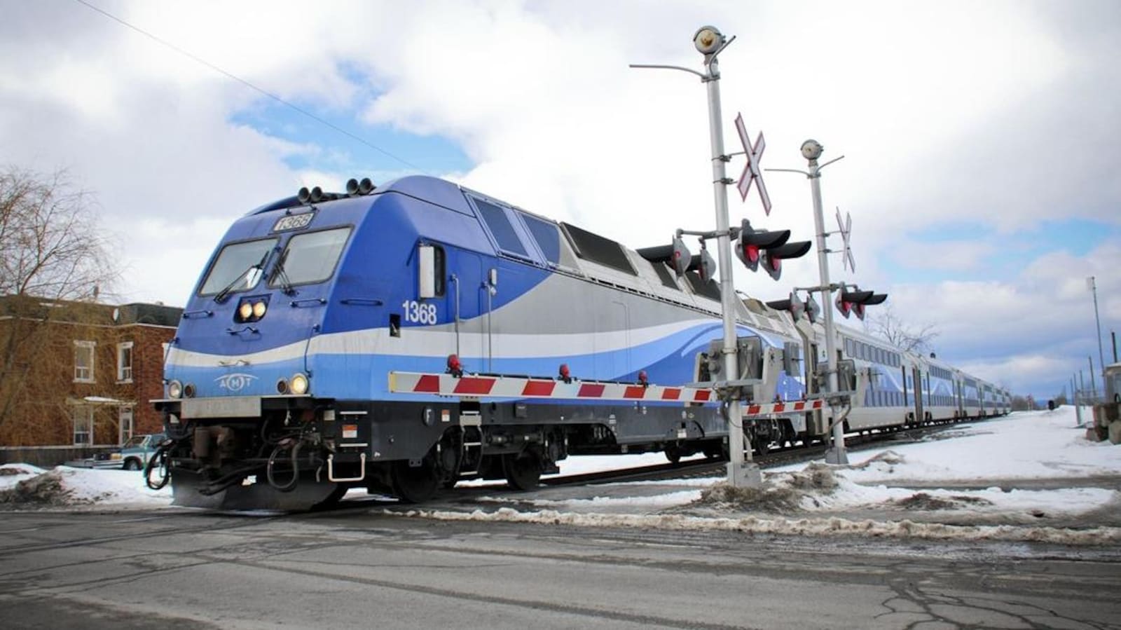 Un train de banlieue d'Exo traverse un passage à niveau, en hiver.