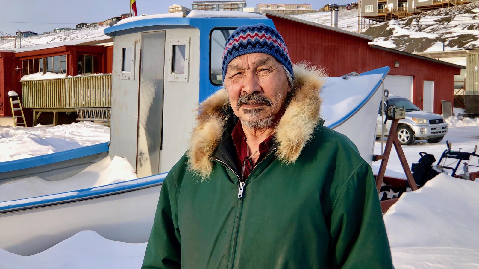 Un homme porte un manteau avec un col de fourrure et une tuque.