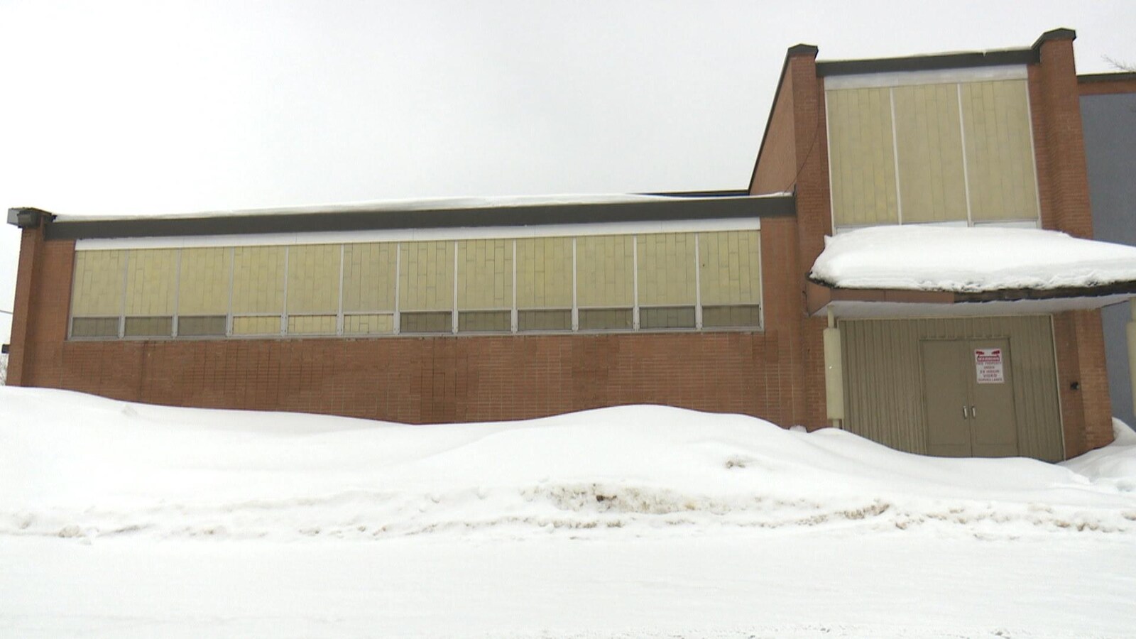 De la neige devant un bâtiment en briques.
