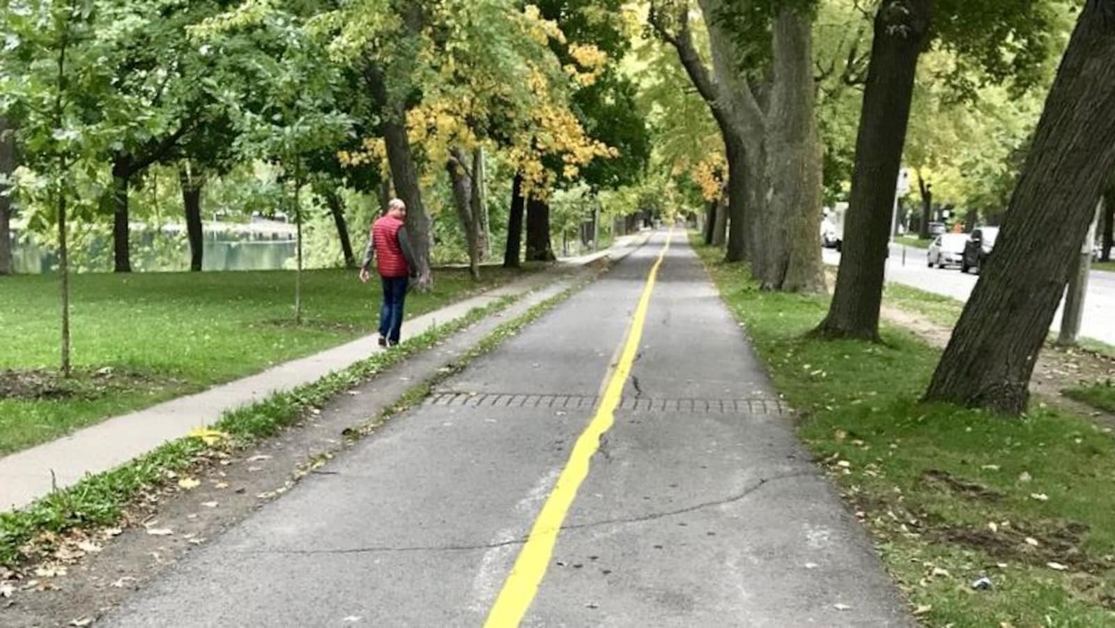 Un homme marche sur un sentier qui longe la piste cyclable.