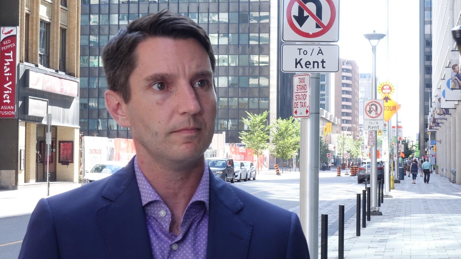 André Fortin en entrevue à Radio-Canada, à l'extérieur, le long d'une rue.