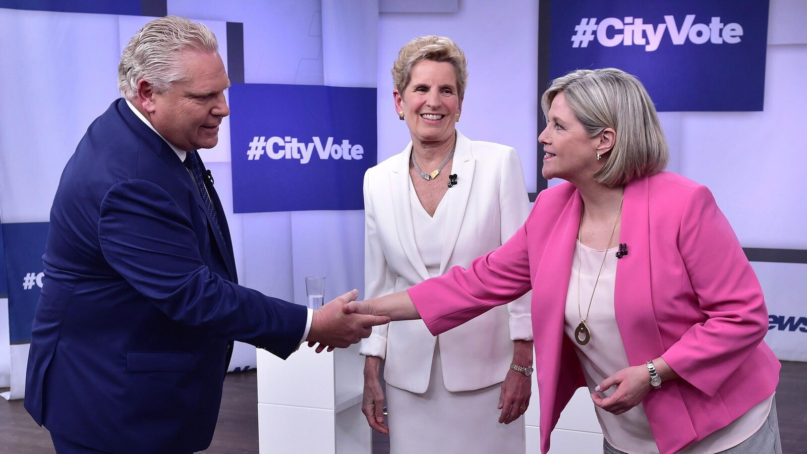 Doug Ford serre la main à Andrea Horwath pendant que Wynne les regarde en souriant.