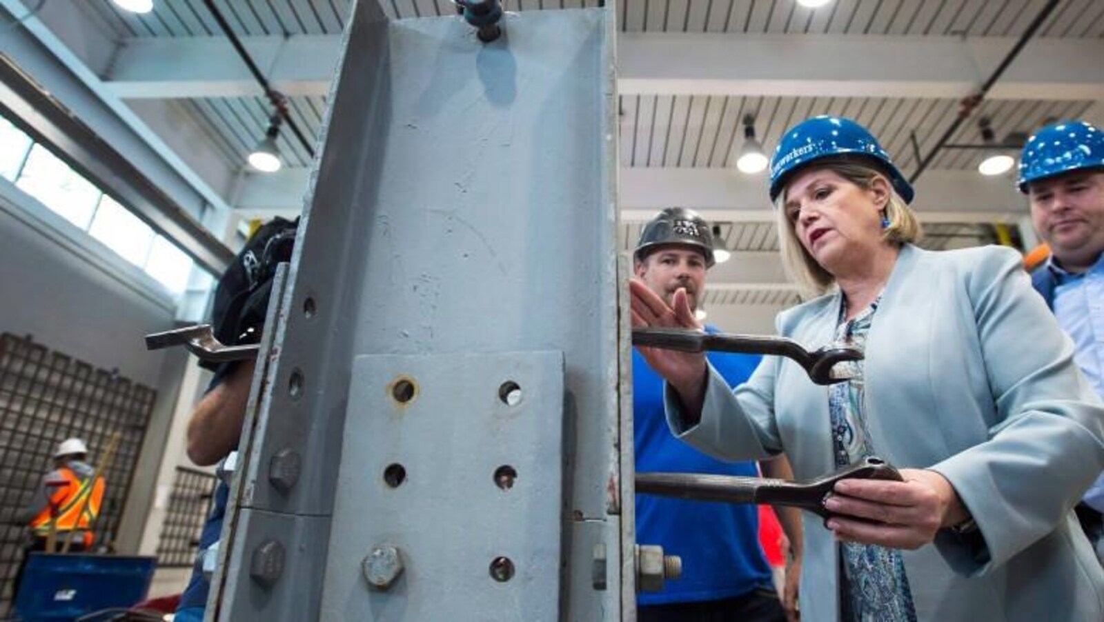 Andrea avec un casque de travail bleu manie un outil