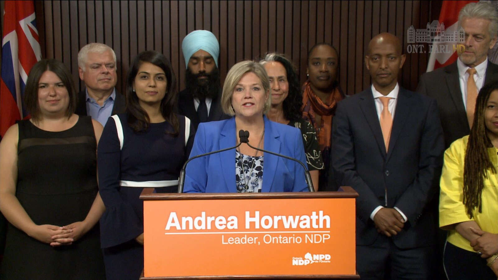 Andrea Horwath derrière un podium et devant un groupe de personnes.