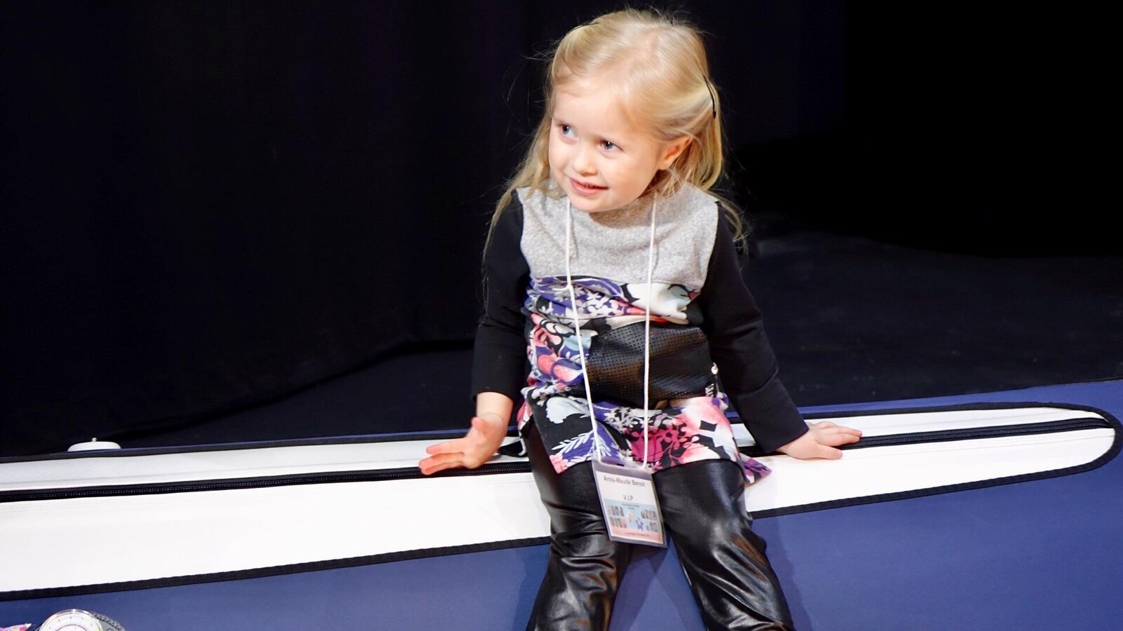 Une petite fille blonde souriante.