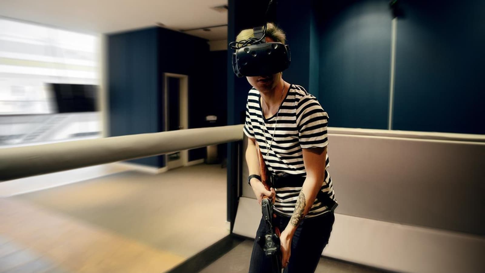 Un joueur armé d'un fusil de plastique et équipé d'un masque de réalité virtuelle joue sur le tapis roulant.