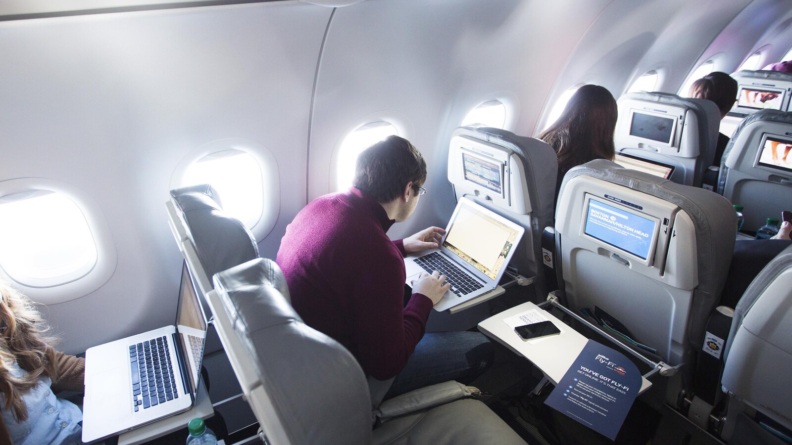 Des passagers s'occupent durant leur vol en utilisant leur ordinateur portable.
