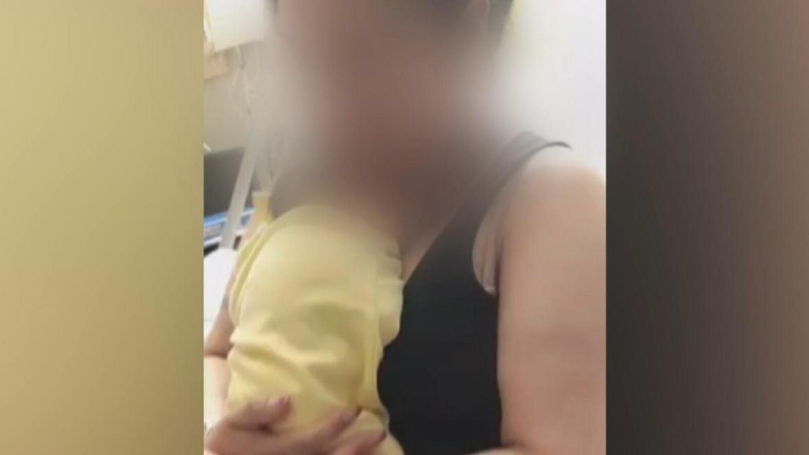 Une femme dont le visage est flouté berce son bébé contre elle.