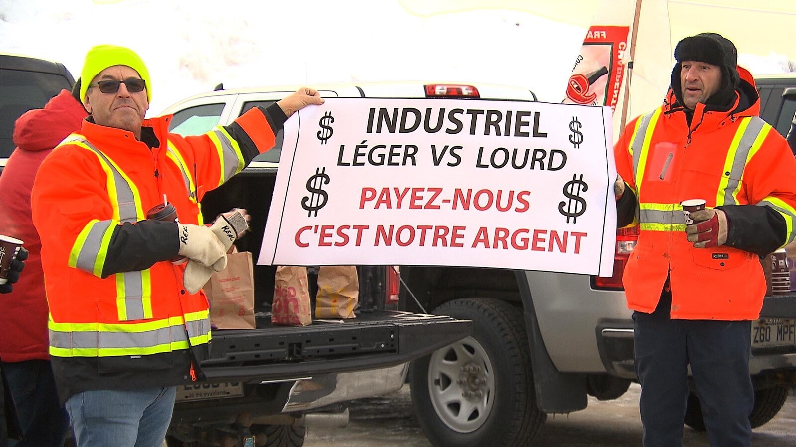Deux manifestants brandissant une pancarte : « Payez-nous c'est notre argent »