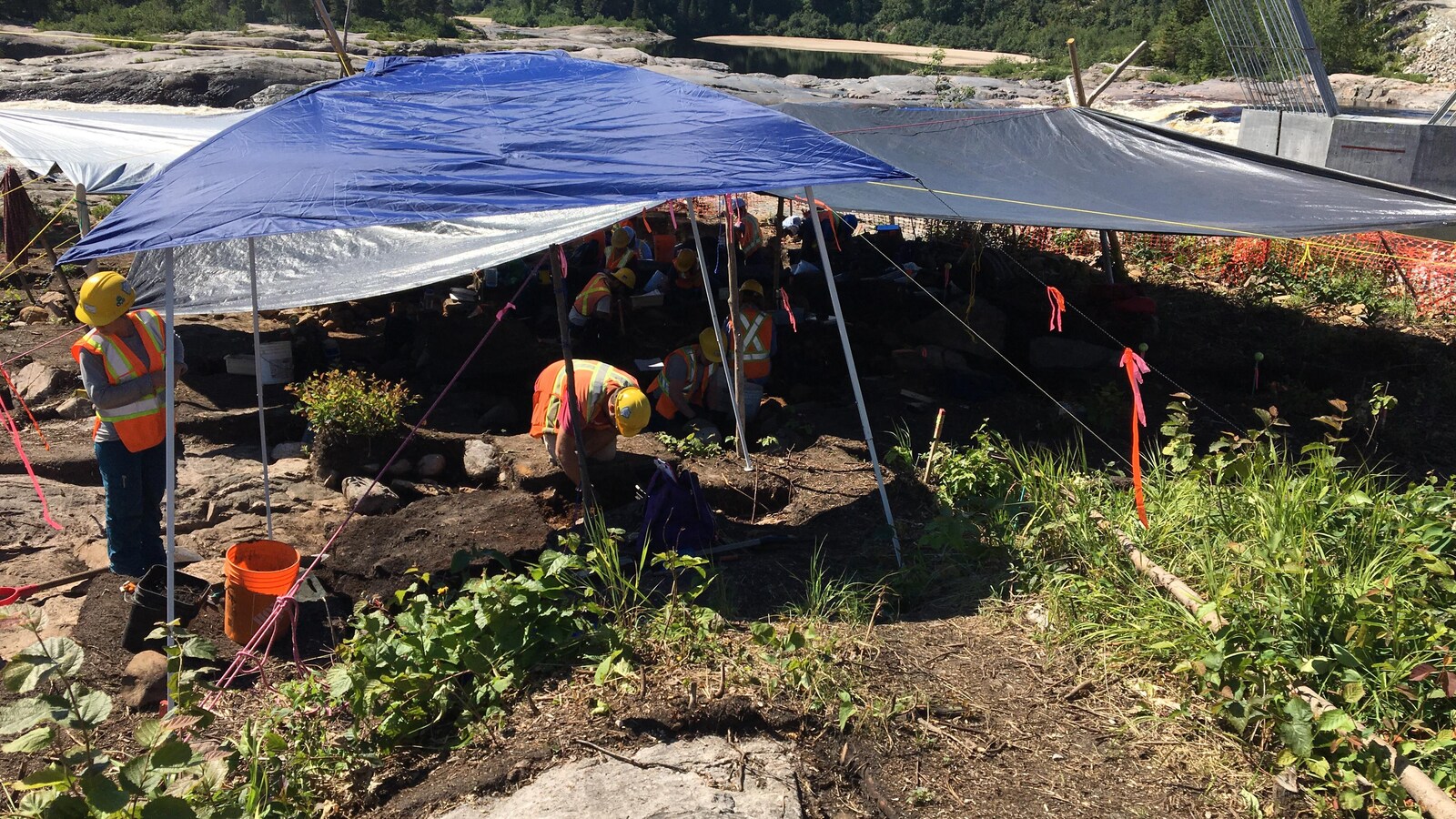 Des travailleurs sous des abris près d'une rivière