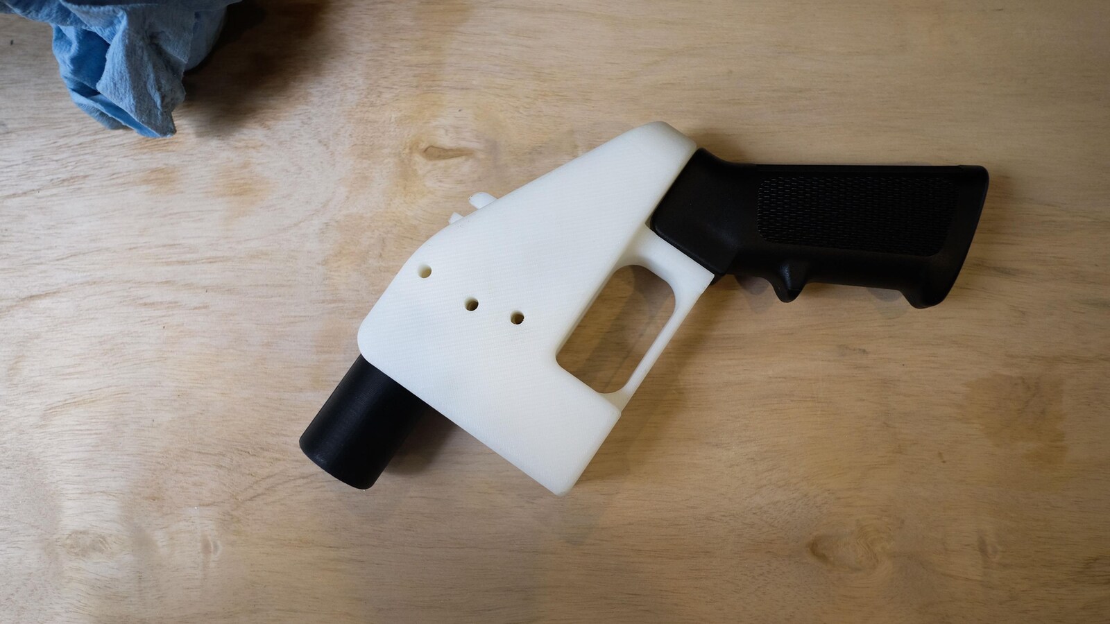 Une petite arme à feu est posée sur une table en bois. Son canon est très court.