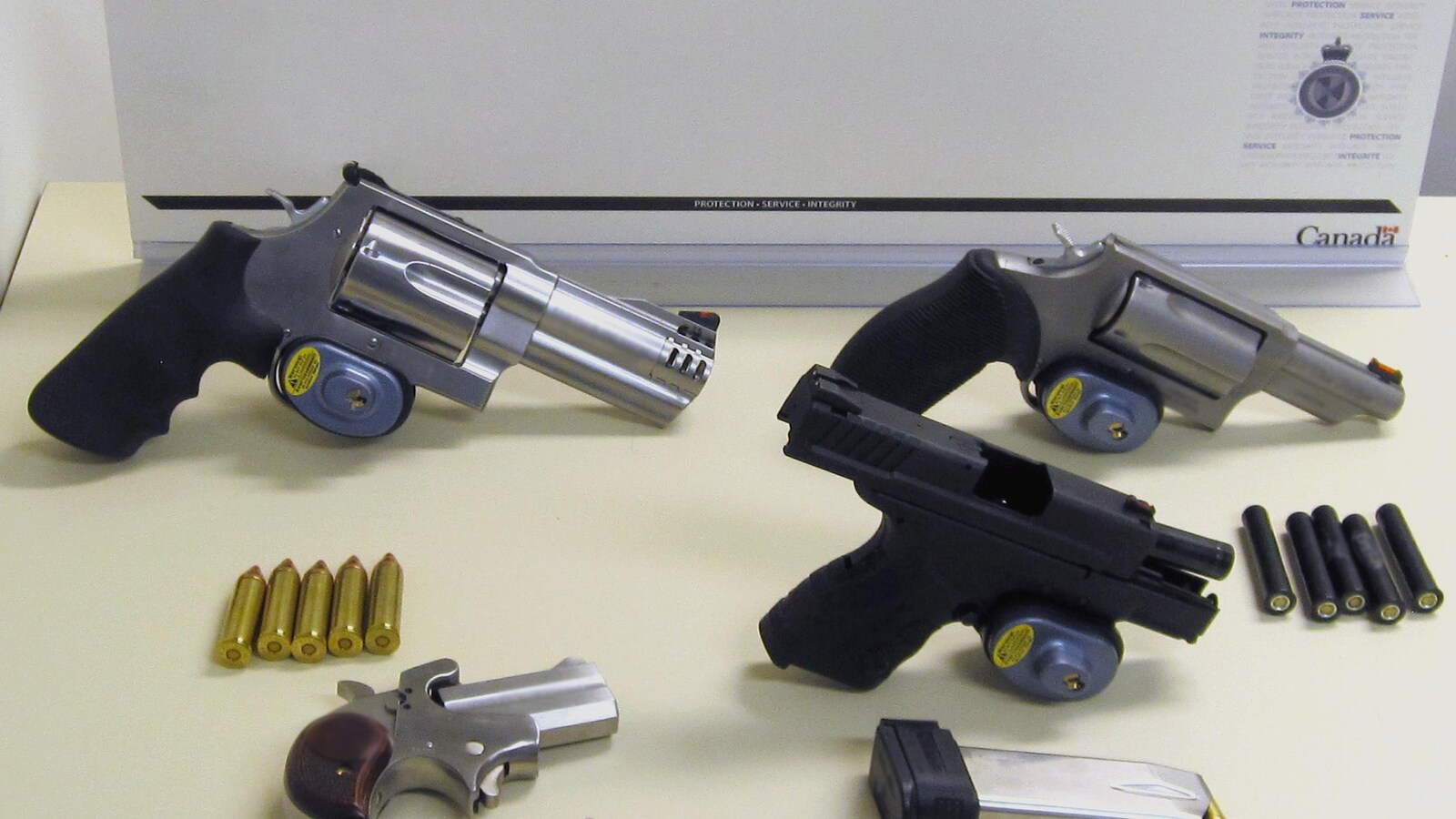 Quatre revolvers et pistolets sur une table.