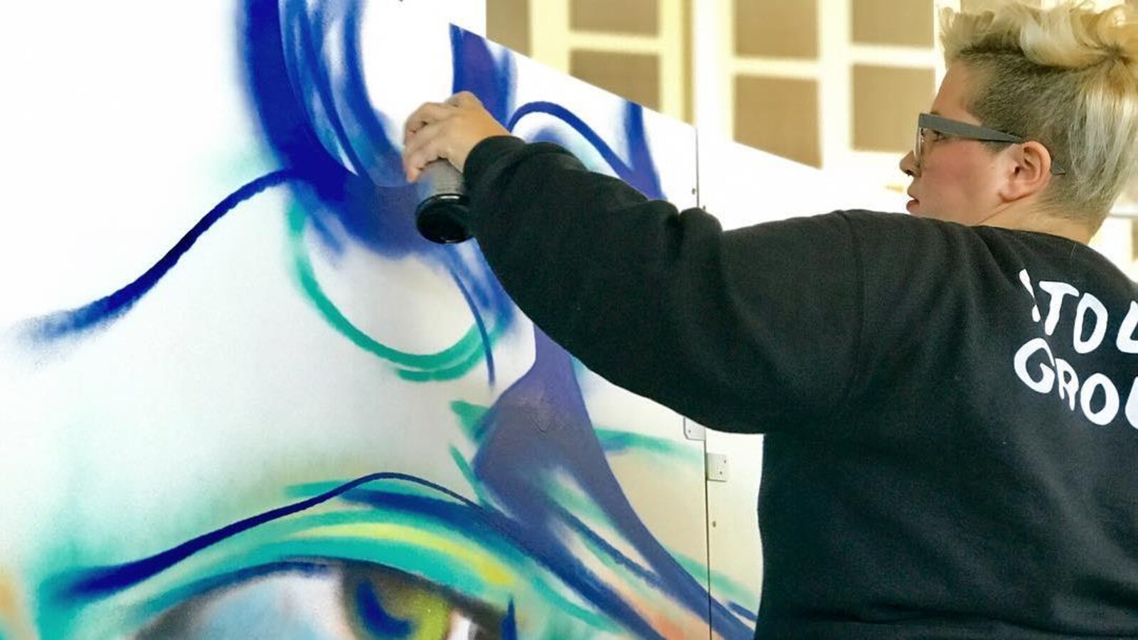 L'artiste Michelle Mique en train de peindre une murale.
