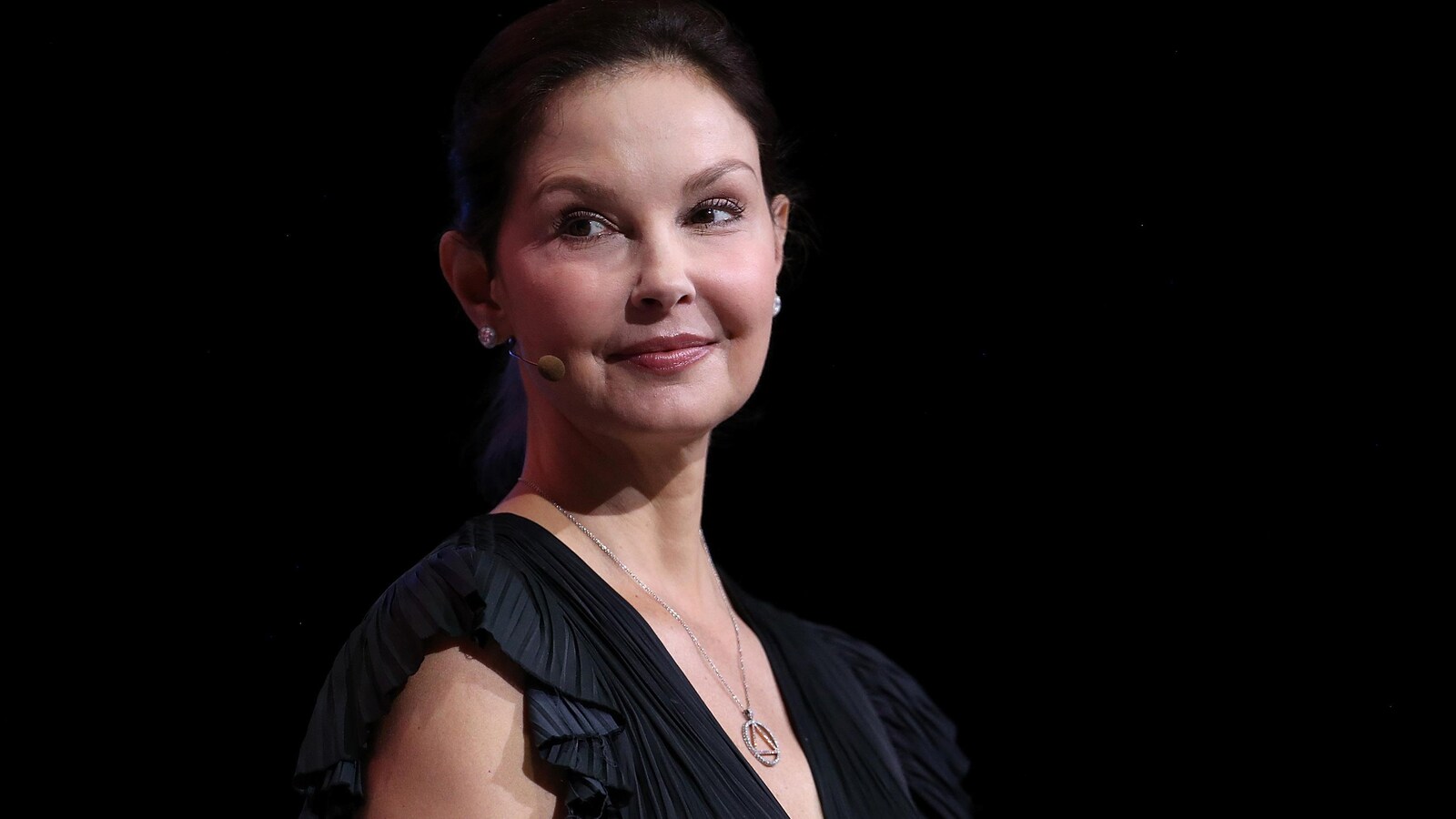 Ashley Judd, souriante sur une scène, le regard vers la gauche