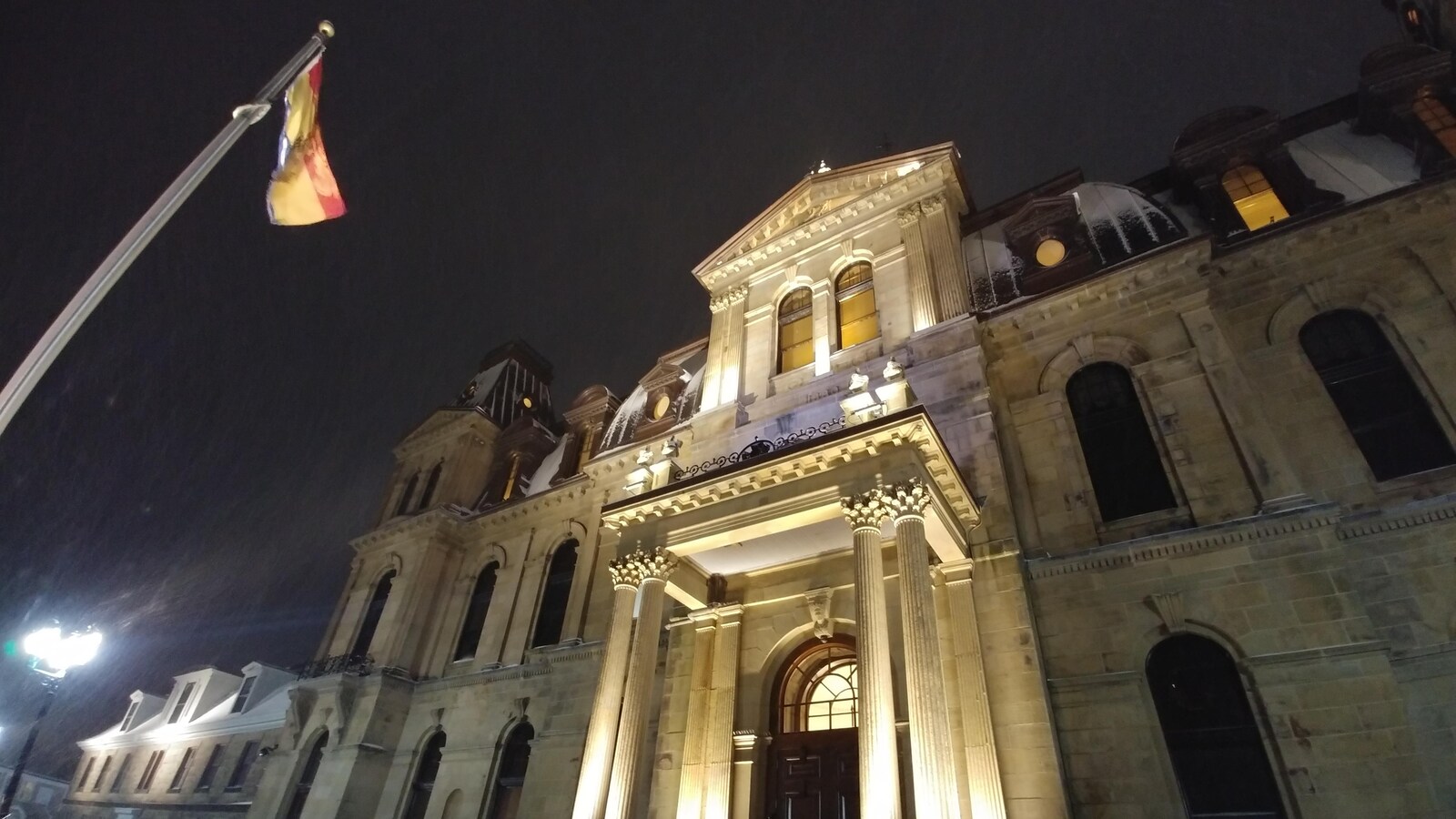 Le bâtiment de l'Assemblée législative vue de l'extérieur, de soir.