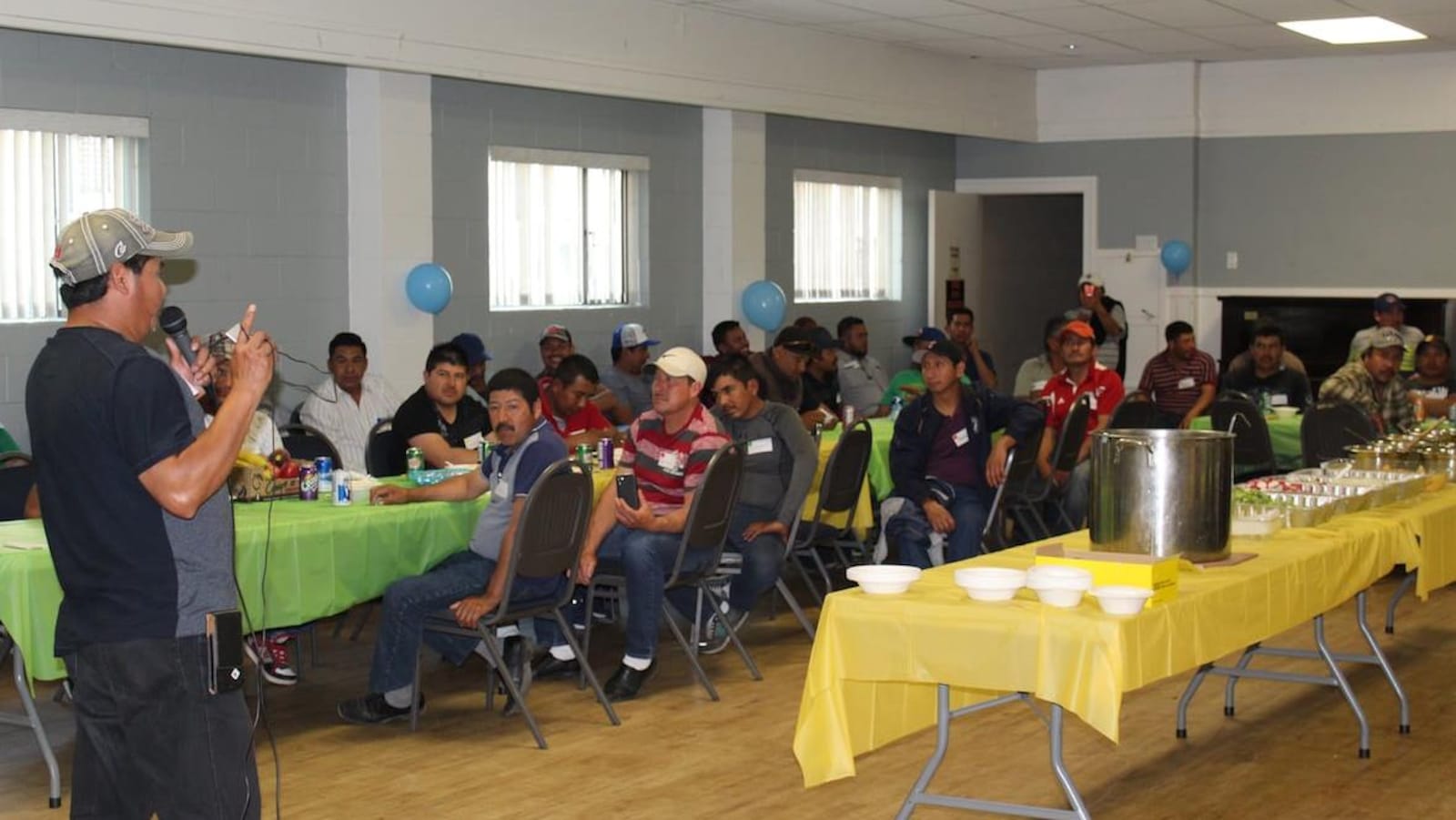 Des travailleurs temporaires étrangers réunis autour d'une table dans une salle à Langley lors d'une rencontre à l'occasion de la fête des Pères.