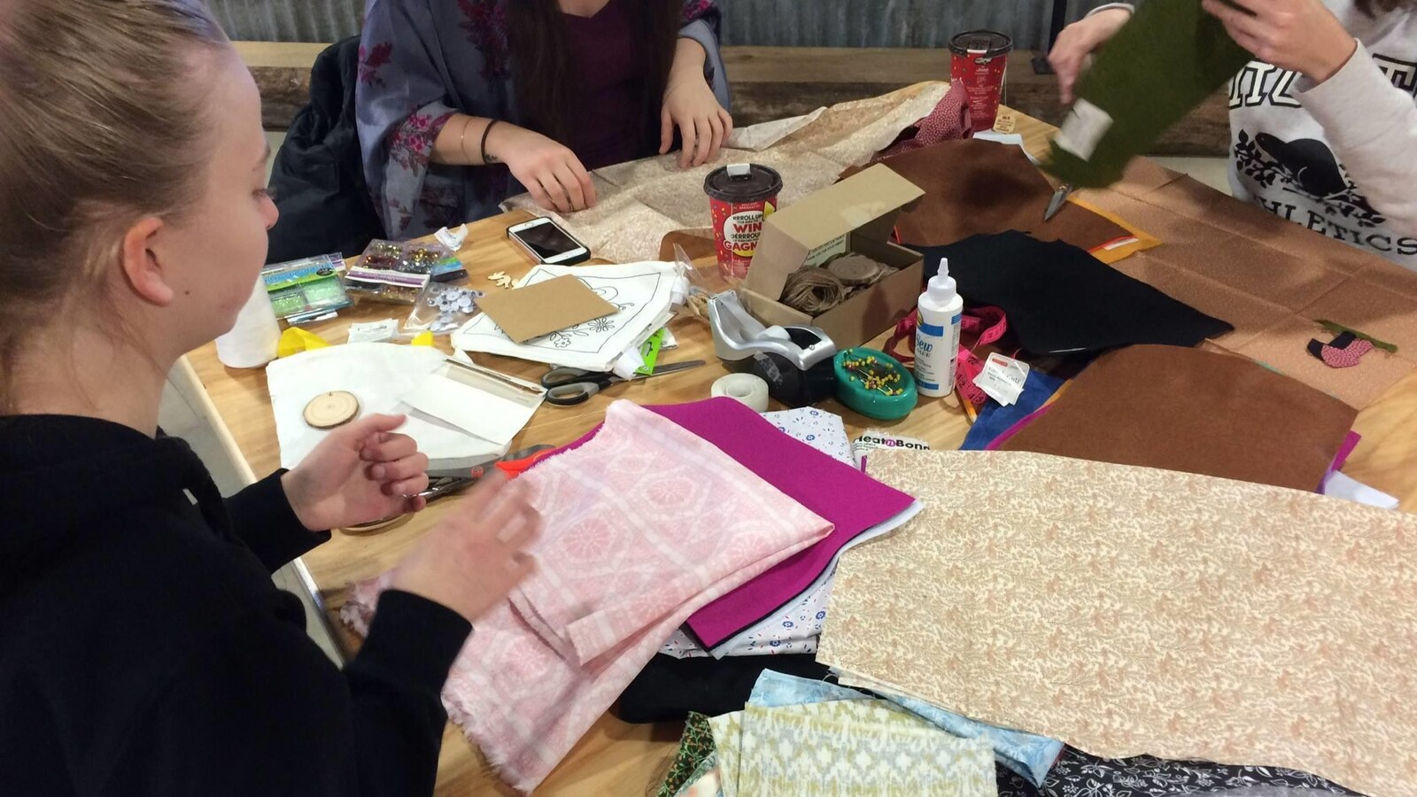 Trois femmes manipulant des morceaux de tissus.