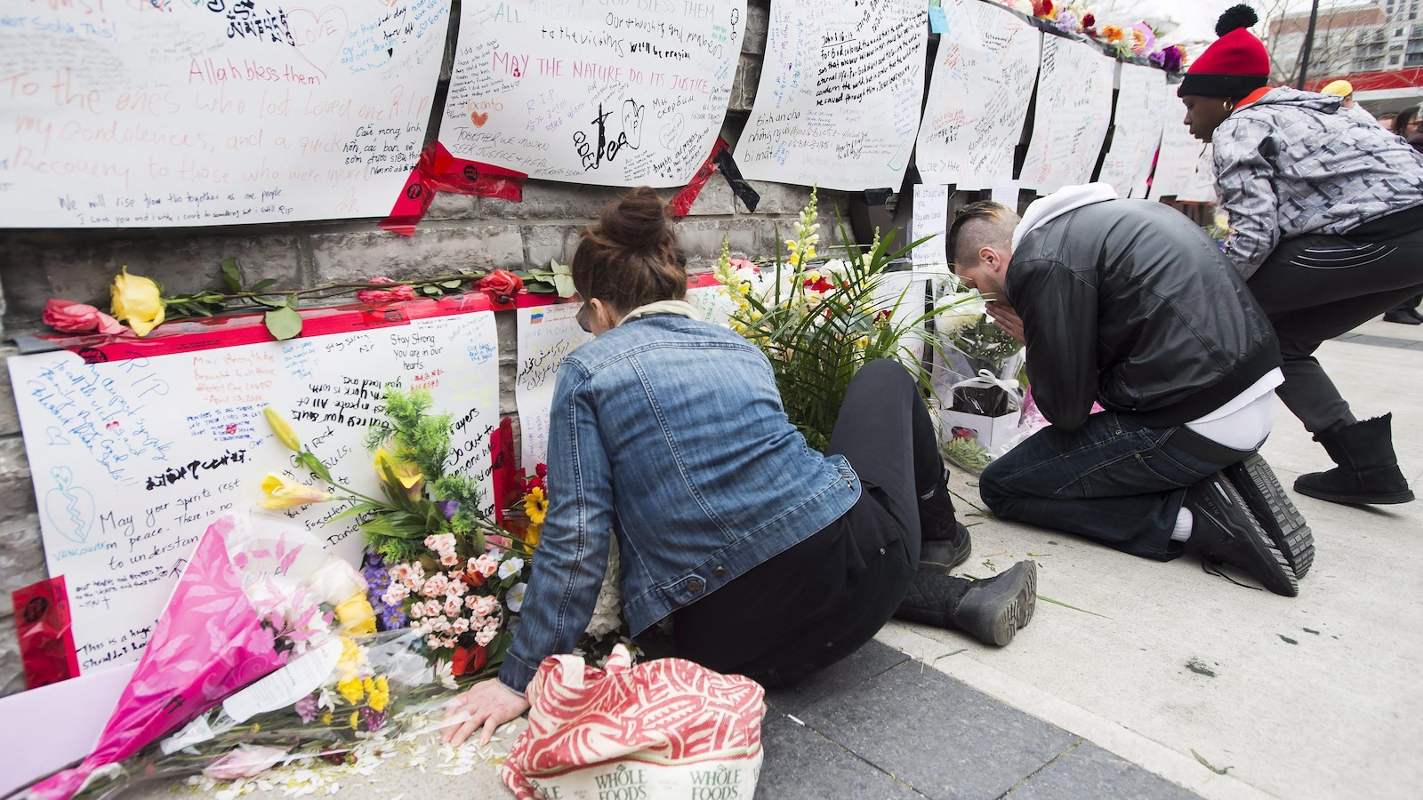 Des gens lisent les messages laissés au mémorial dans un parc du nord de Toronto.