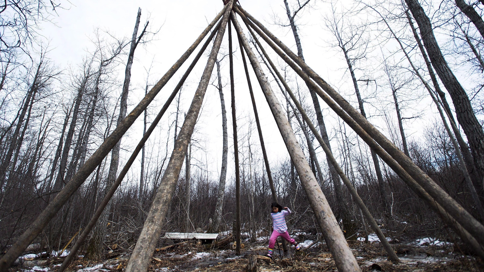 Une petite fille joue dans un tipi dans la forêt près d'Attawapiskat.