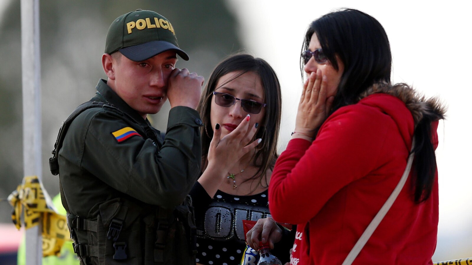 Un policier et deux femmes pleurent près du lieu de l'explosion, à Bogota, jeudi.