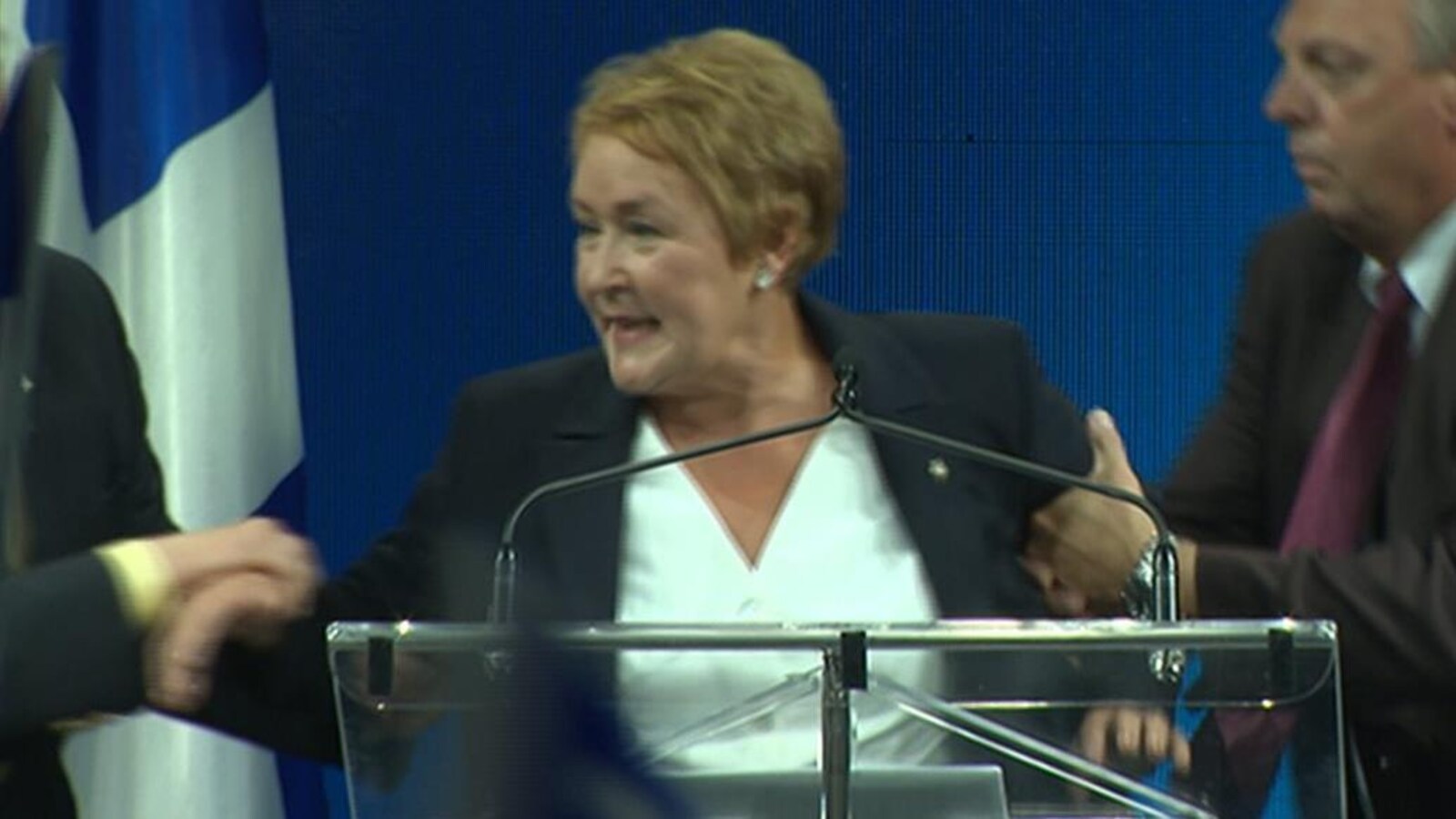 Deux gardes de sécurité évacuent Pauline Marois du pupitre sur la scène du Métropolis